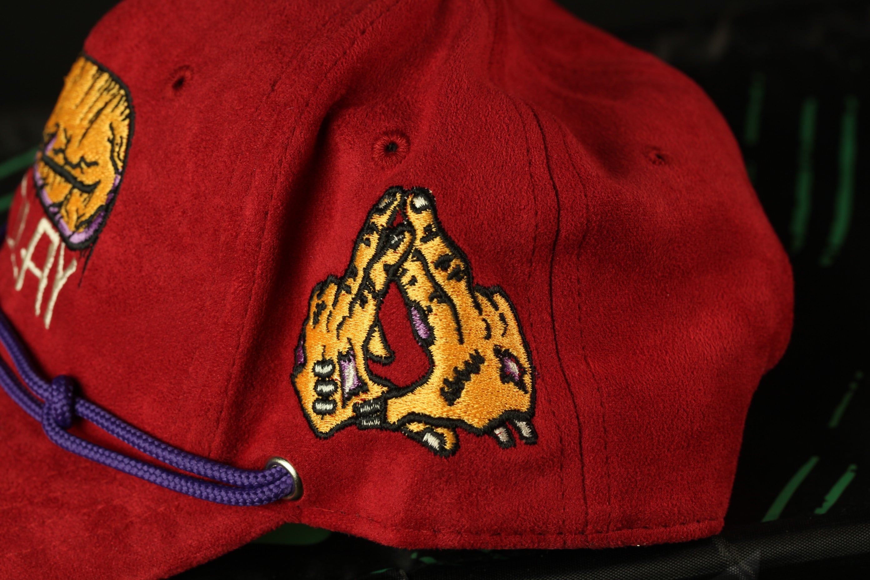 A close-up view of a red baseball cap with a yellow and black graphic design on the side.