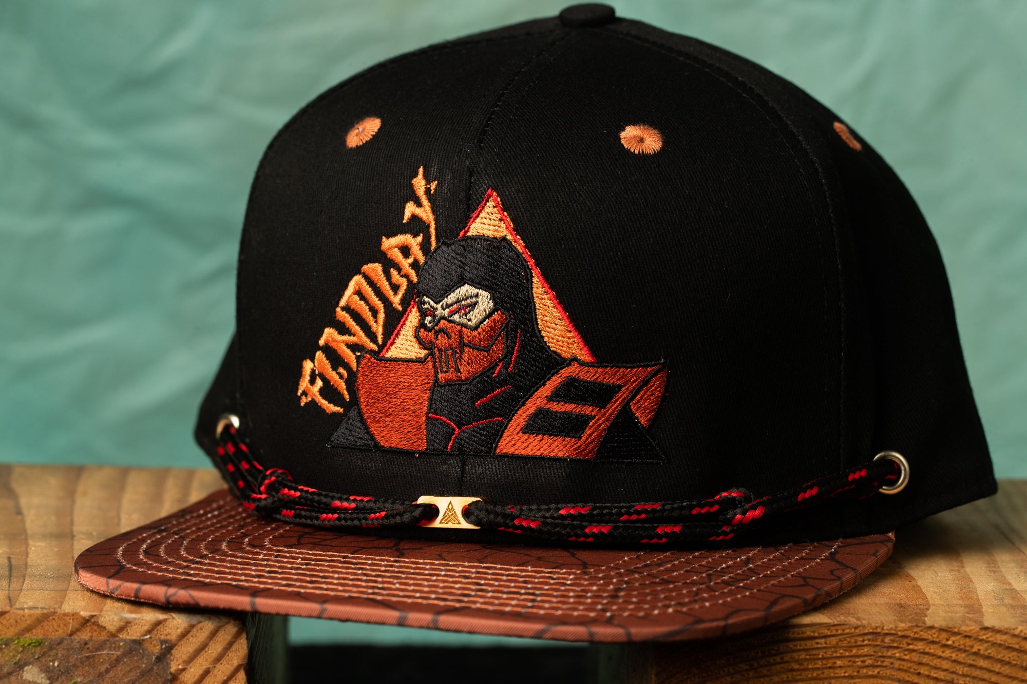 A black baseball cap with a graphic design featuring a character wearing a mask and the word "INDY" printed on it.