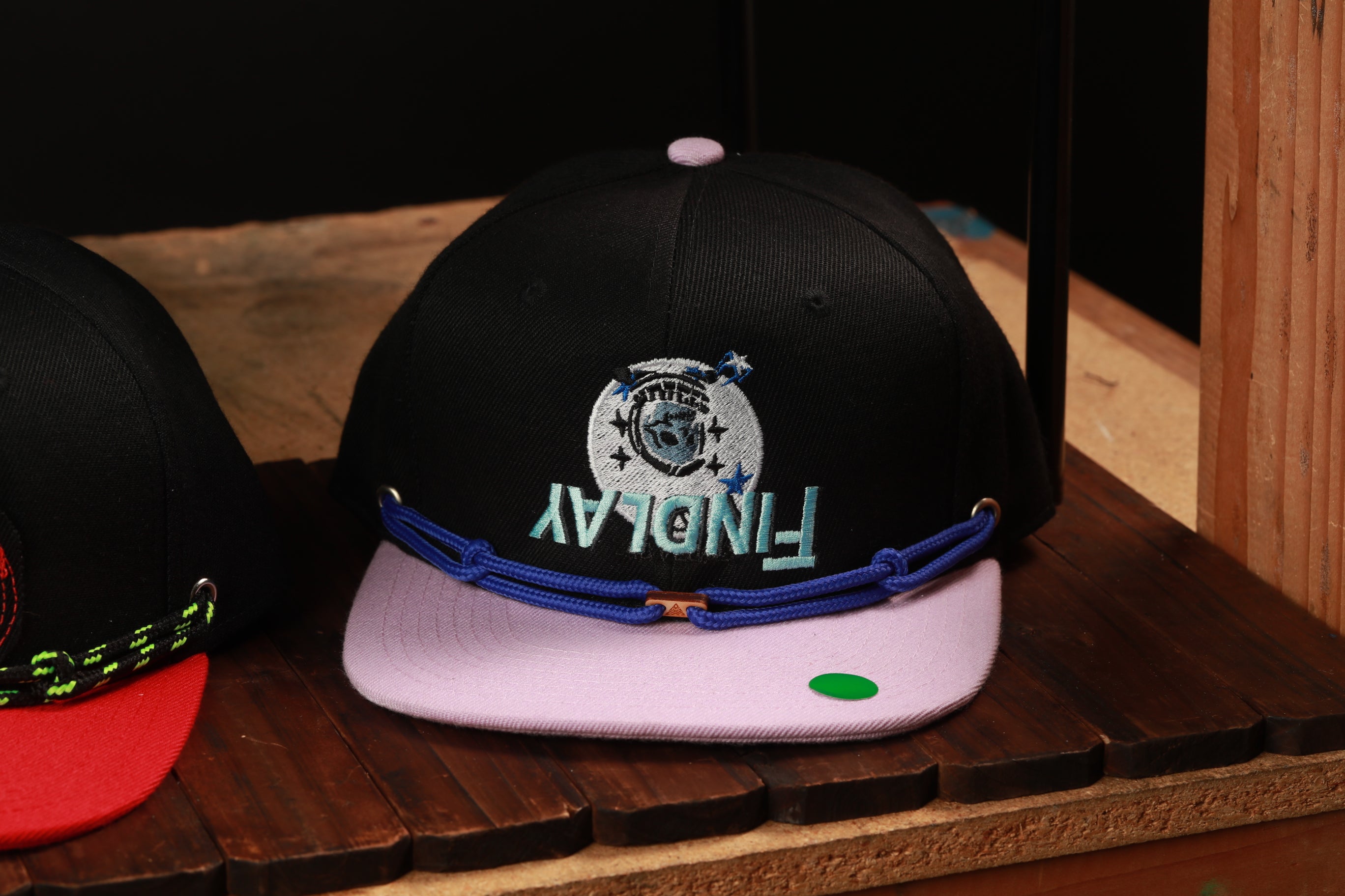 A black baseball cap with a blue and white logo on it, sitting on a wooden surface.