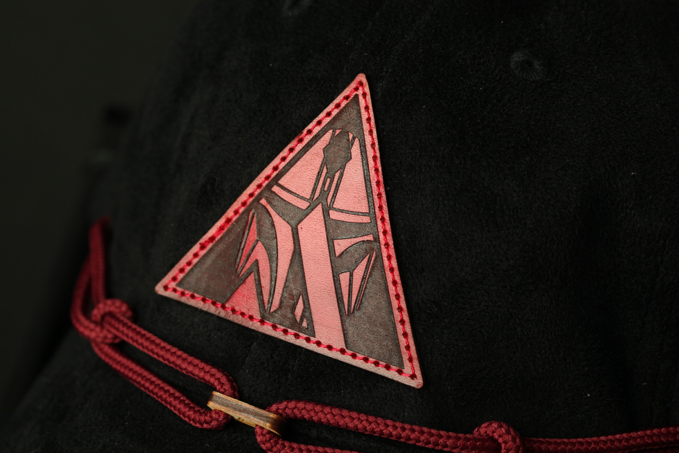 A close-up view of a black fabric with a red triangular patch featuring a stylized design on it.