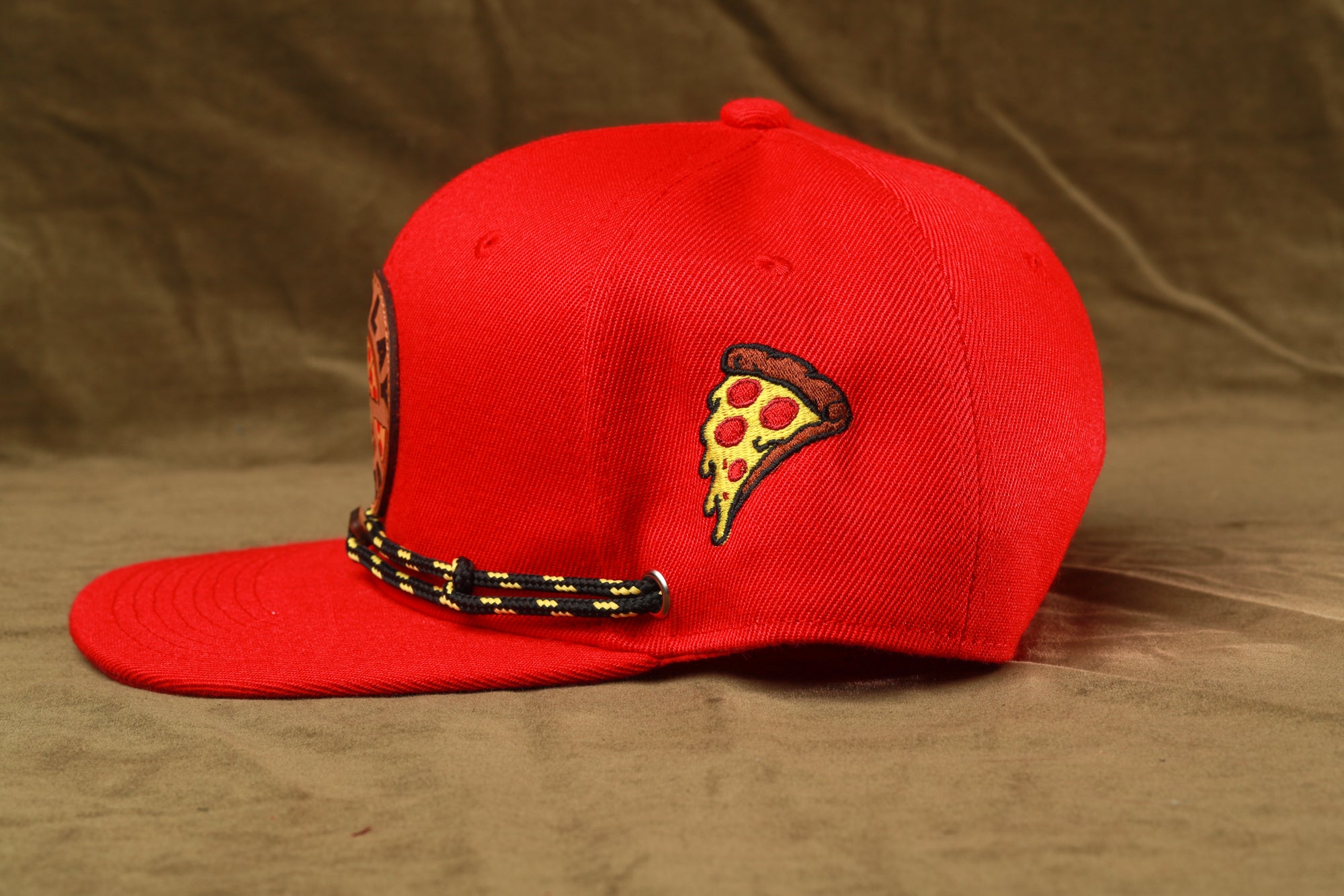 A red baseball cap with a pizza slice embroidered on the side.