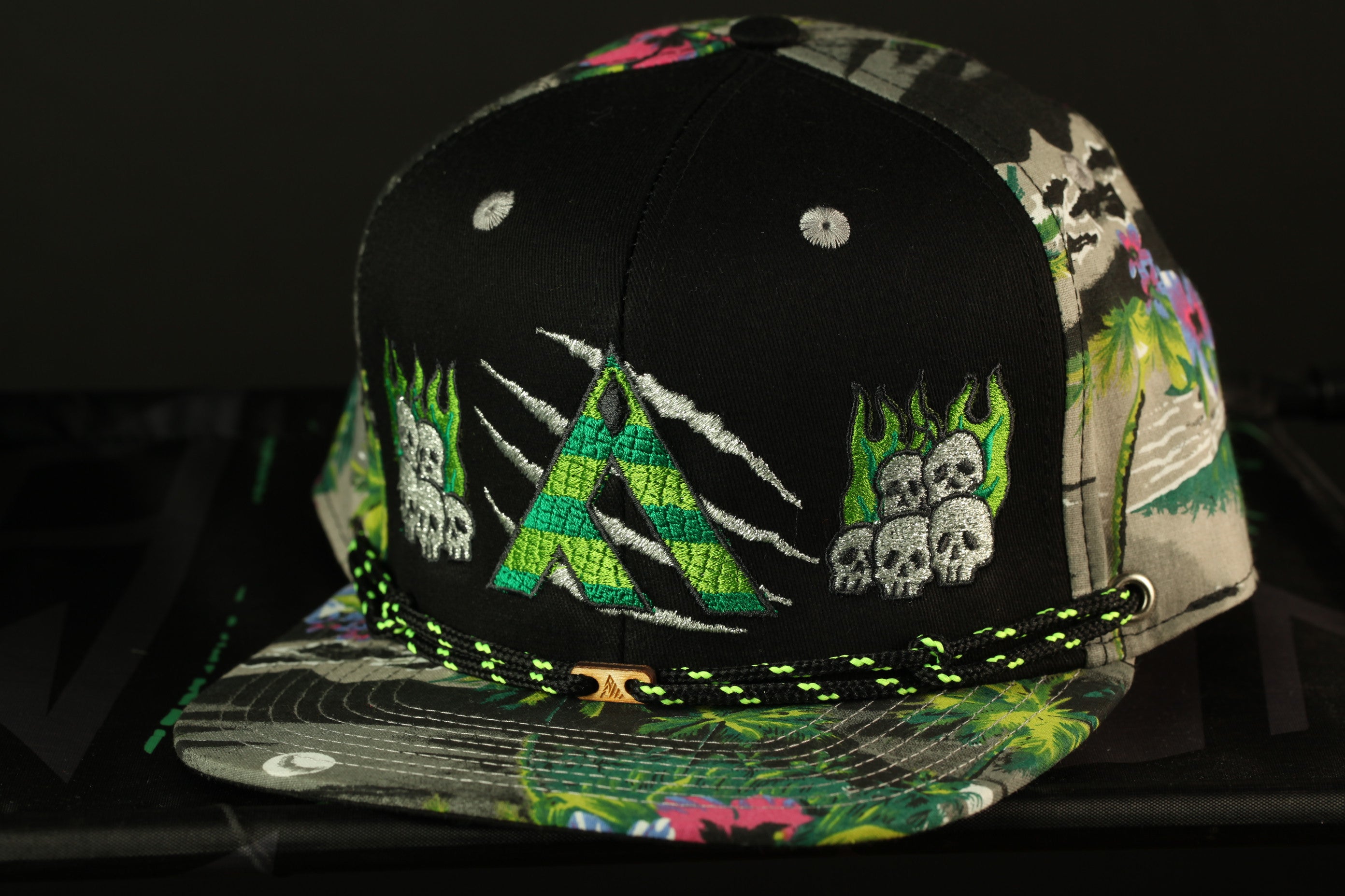 A colorful, patterned baseball cap with a black brim and a green and black braided strap.