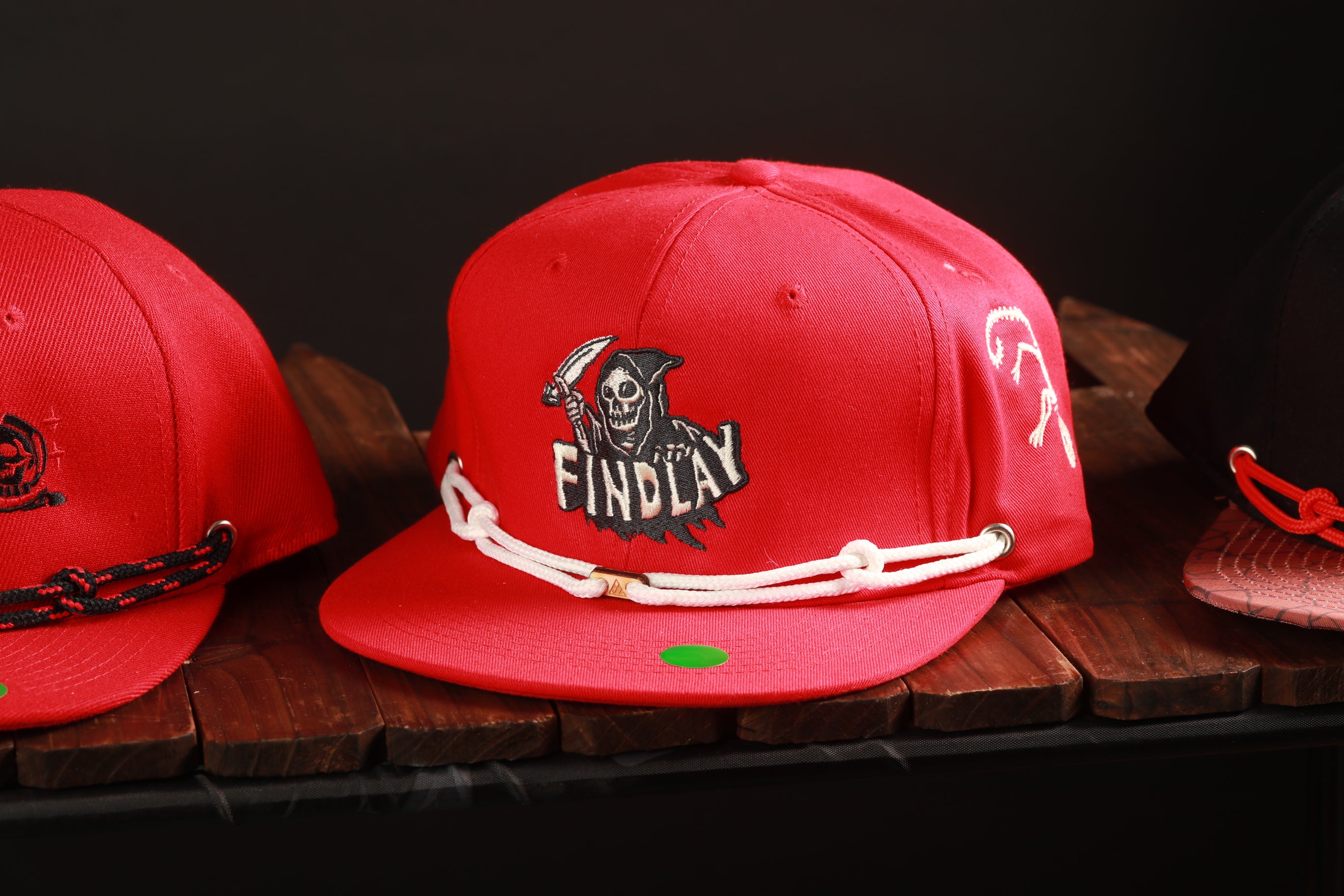 A red baseball cap with a skull and crossbones logo, sitting on a wooden surface.