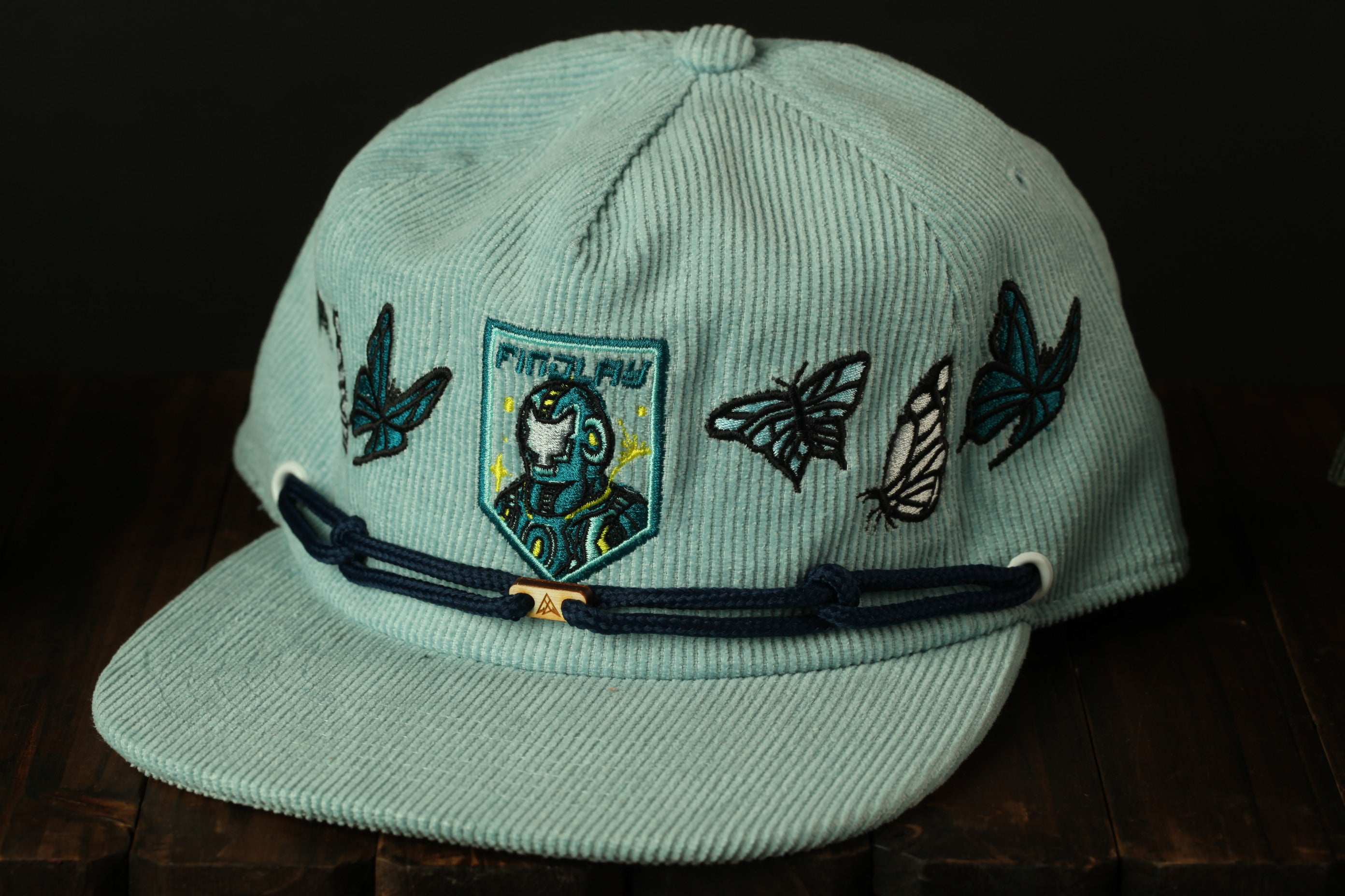A light blue baseball cap with a patch featuring a character and butterflies on the front.