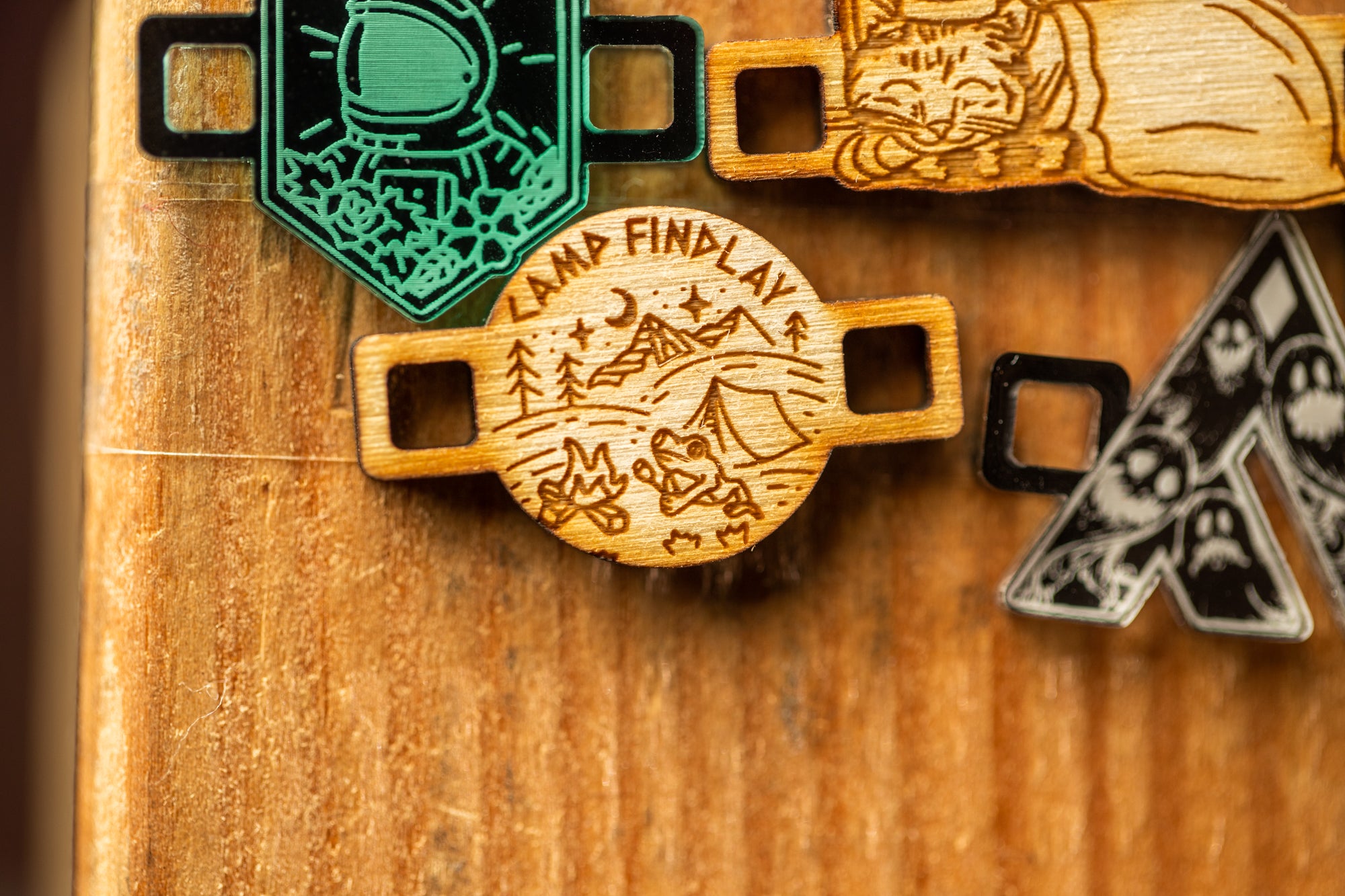 a wooden surface with various engraved or printed objects, including a circular wooden object with a design and text, and other wooden objects with different designs and text.