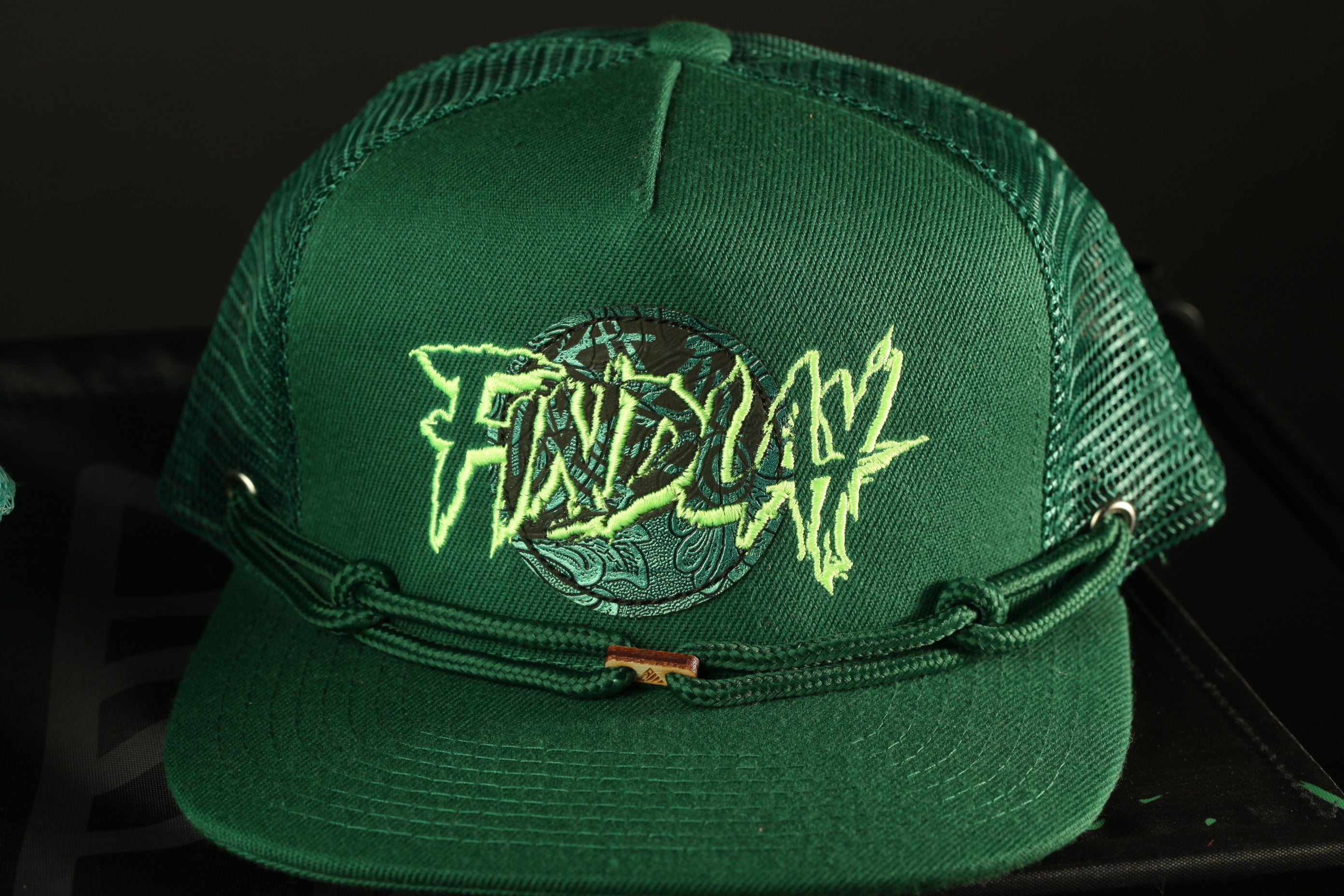A green baseball cap with a graphic design on it.