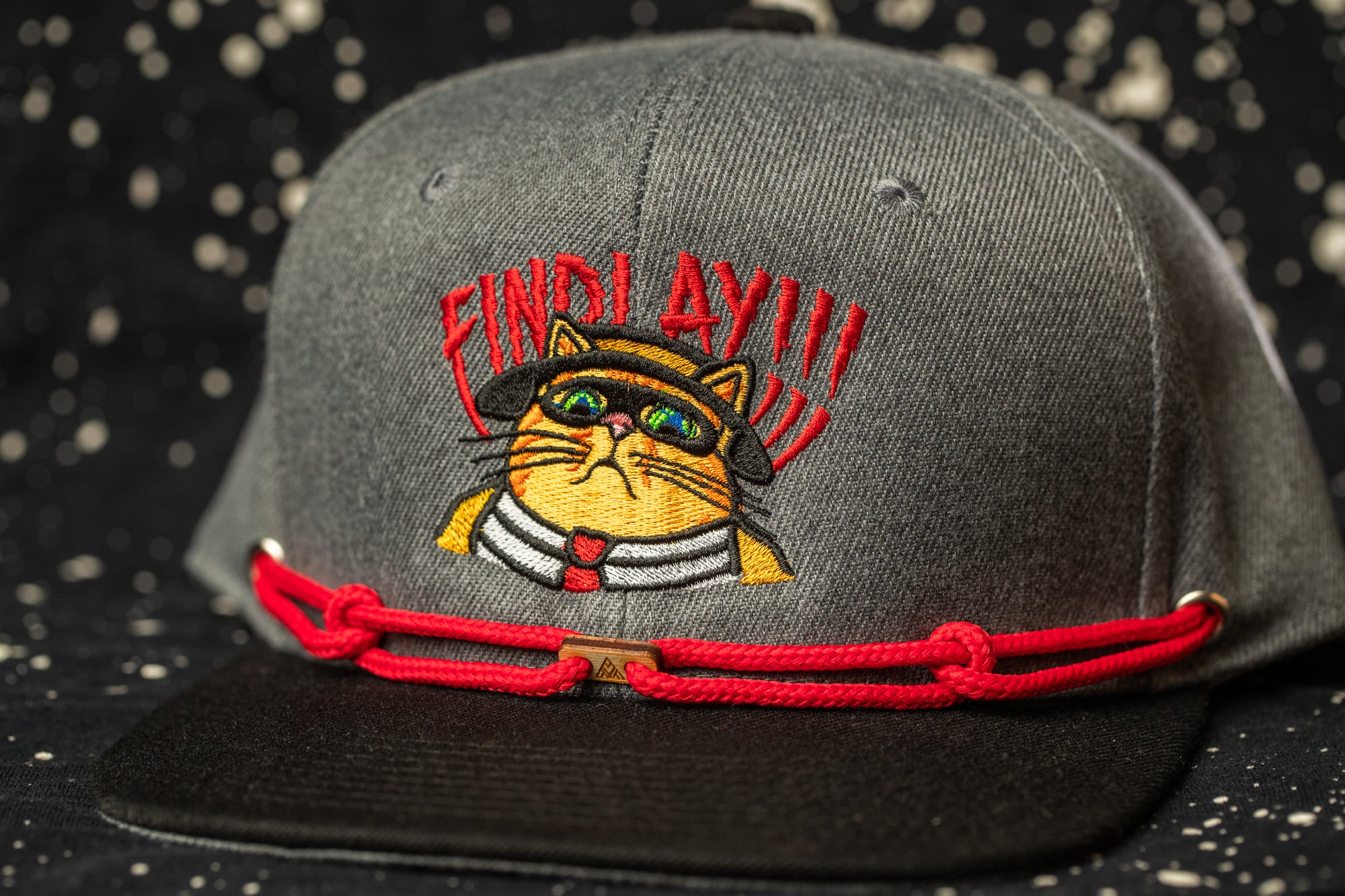 A gray baseball cap with a cat embroidered on it, wearing a red bandana and sunglasses, and the text "FIND LAYAY" on the front.