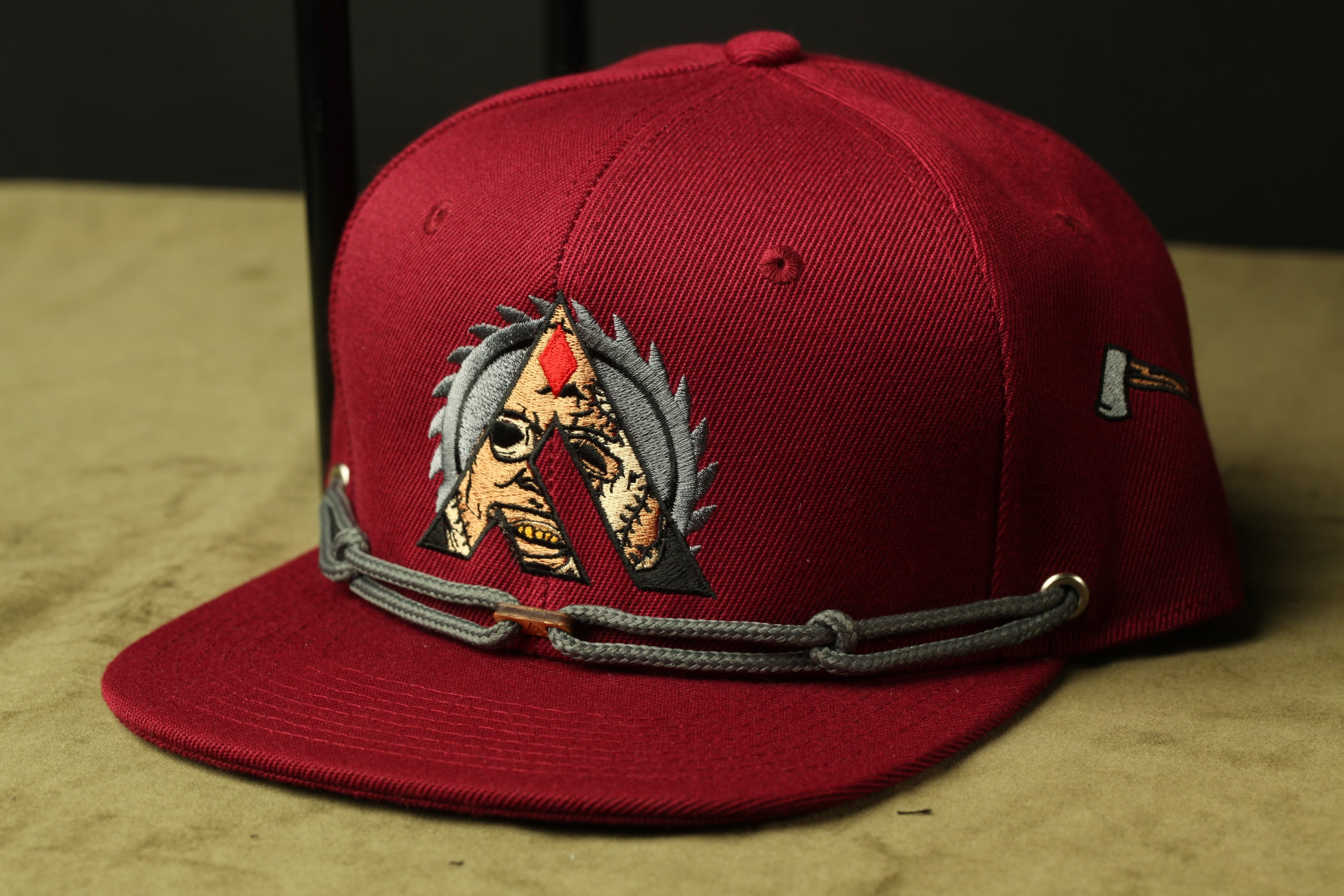 A red baseball cap with a unique logo and a chain strap.