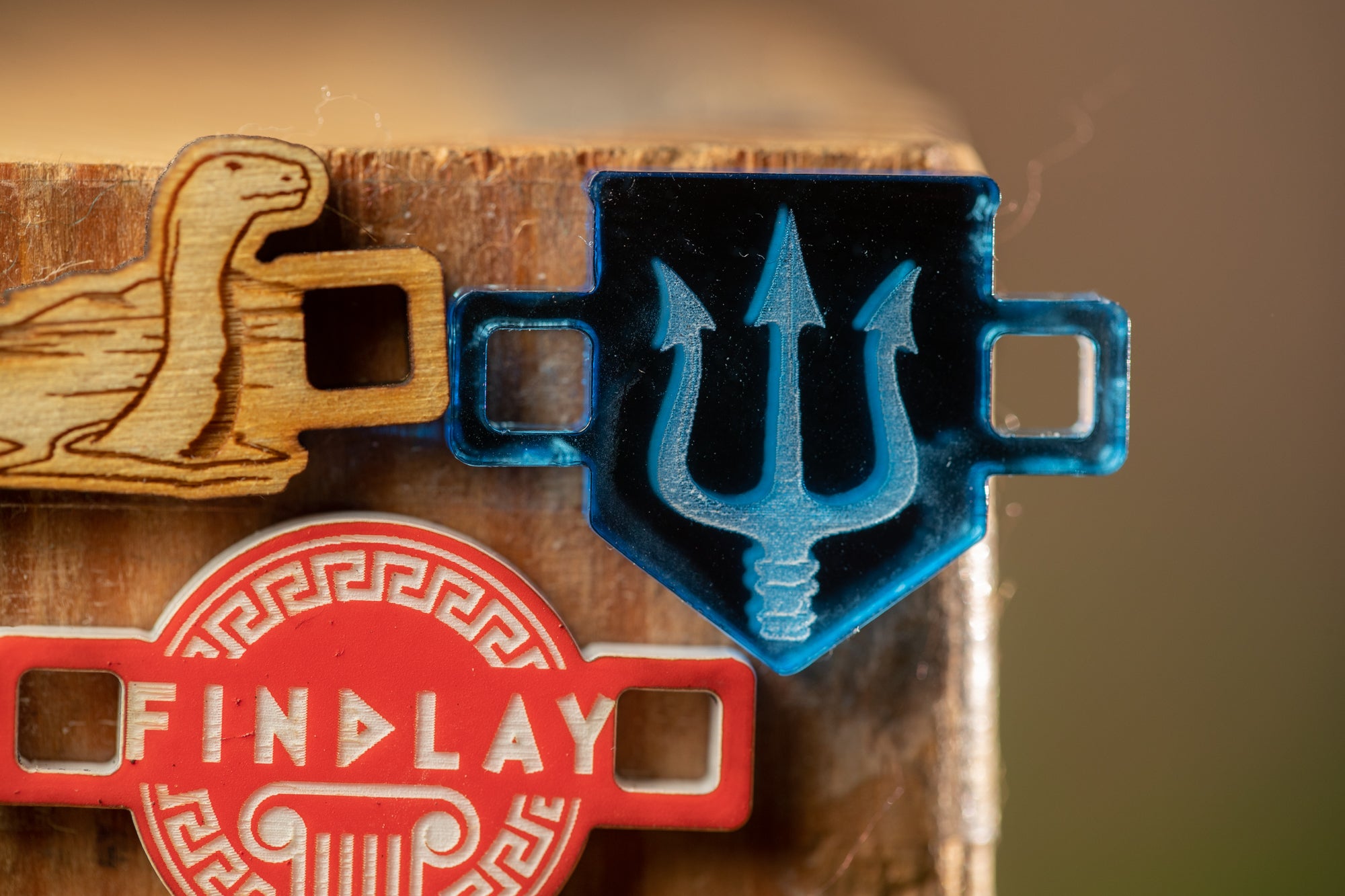 a close-up view of a wooden surface with various objects, including a blue trident-shaped object, a wooden object with a lion design, and a red object with the word "FINDA" written on it.