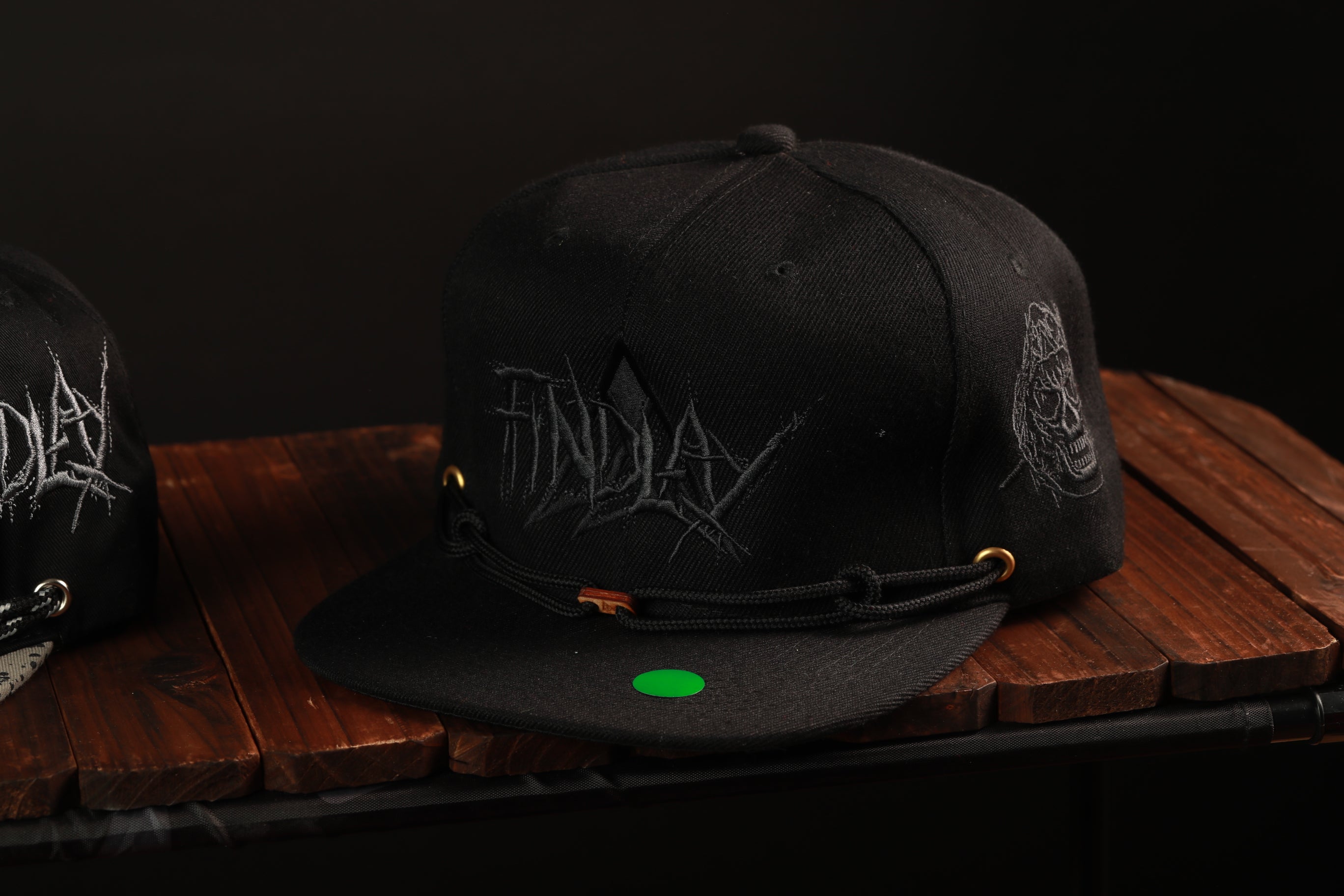A black baseball cap with the word "FINDAY" printed on it, sitting on a wooden surface.