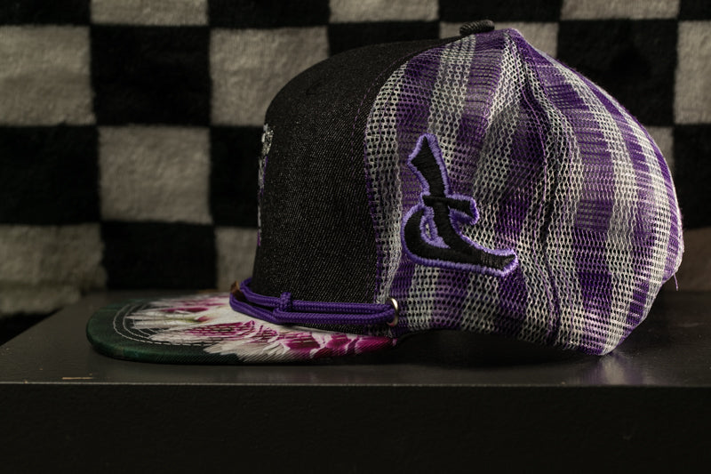 A purple and black baseball cap with a checkered pattern and a purple logo on the side, placed on a black surface against a checkered background.