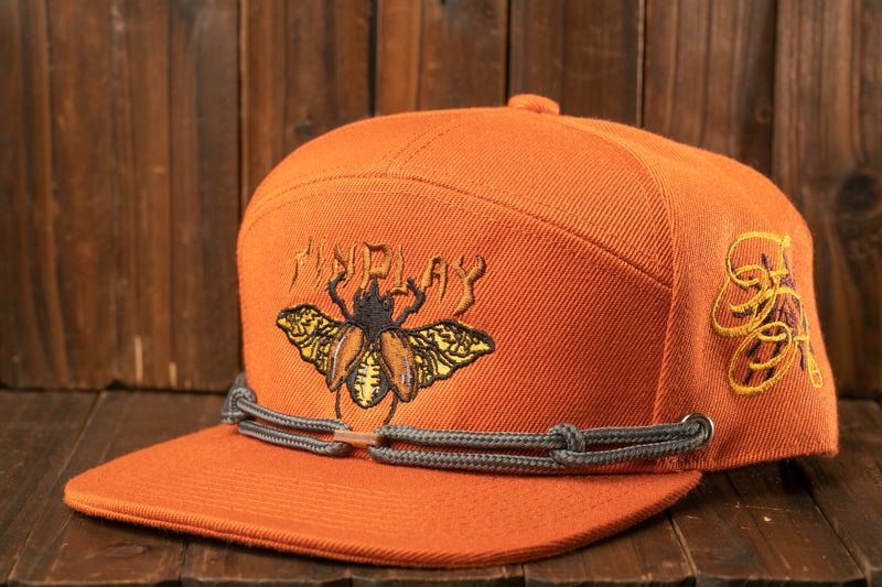 An orange baseball cap with a detailed embroidered design of a bee on the front.