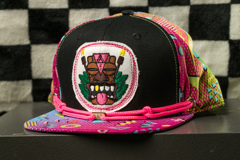 A colorful, patterned baseball cap with a tiki mask design on the front.