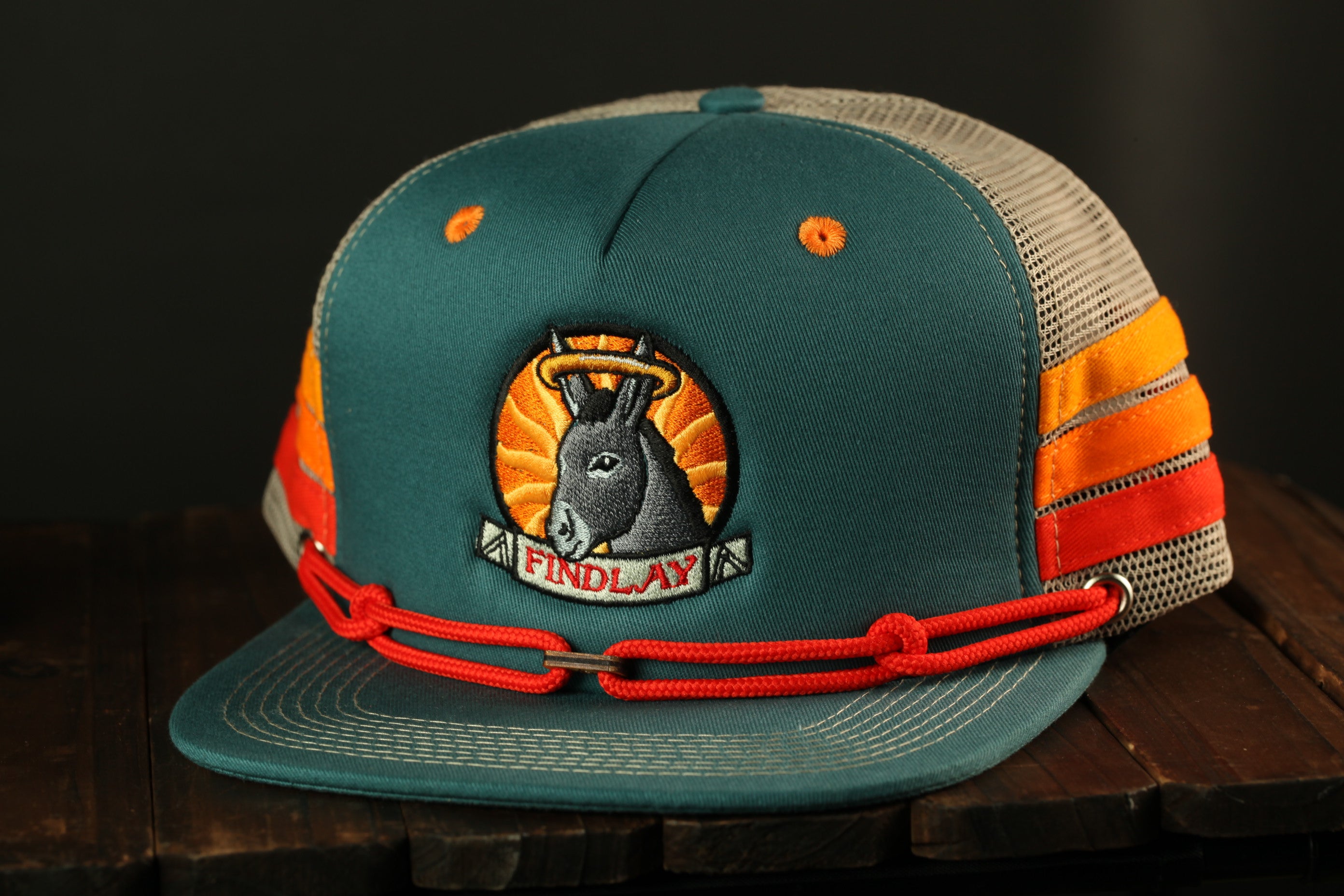 A green baseball cap with a red chain and a logo featuring a donkey wearing a halo.