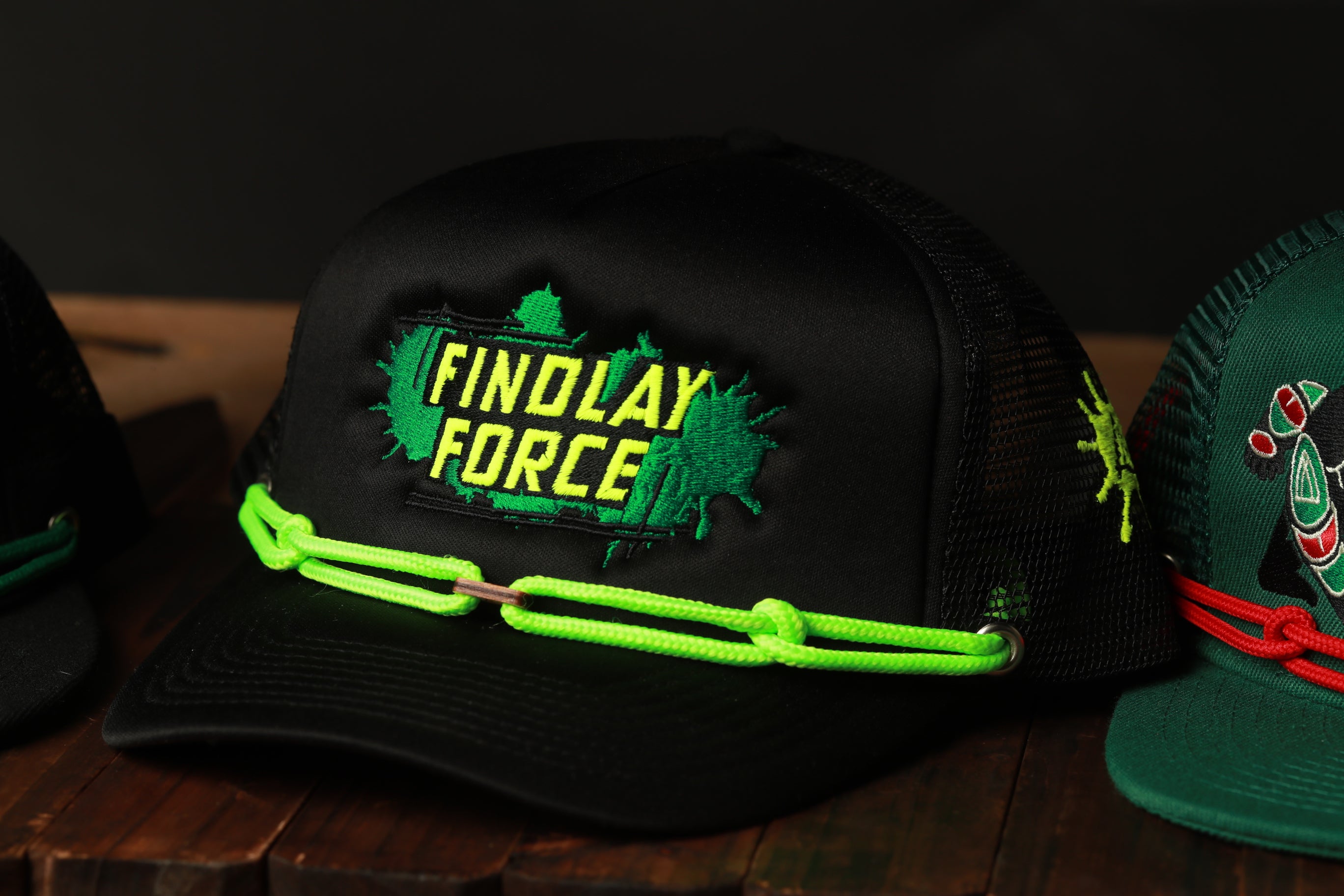 A black baseball cap with neon green and yellow accents, featuring the text "FINDLAY FORCE" on the front.