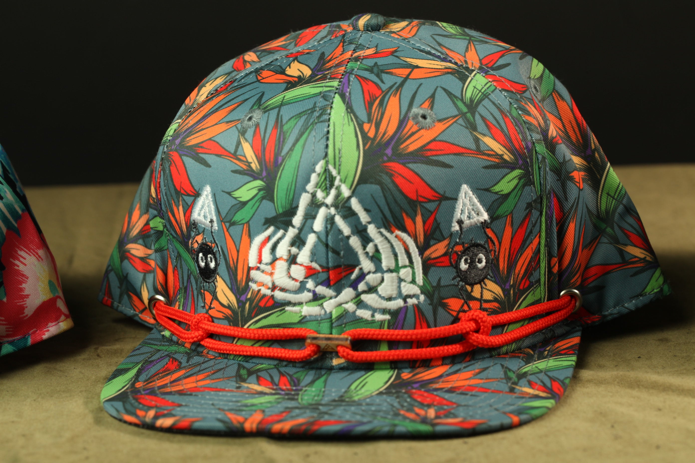 A colorful, patterned baseball cap with a floral design and a skeleton motif.
