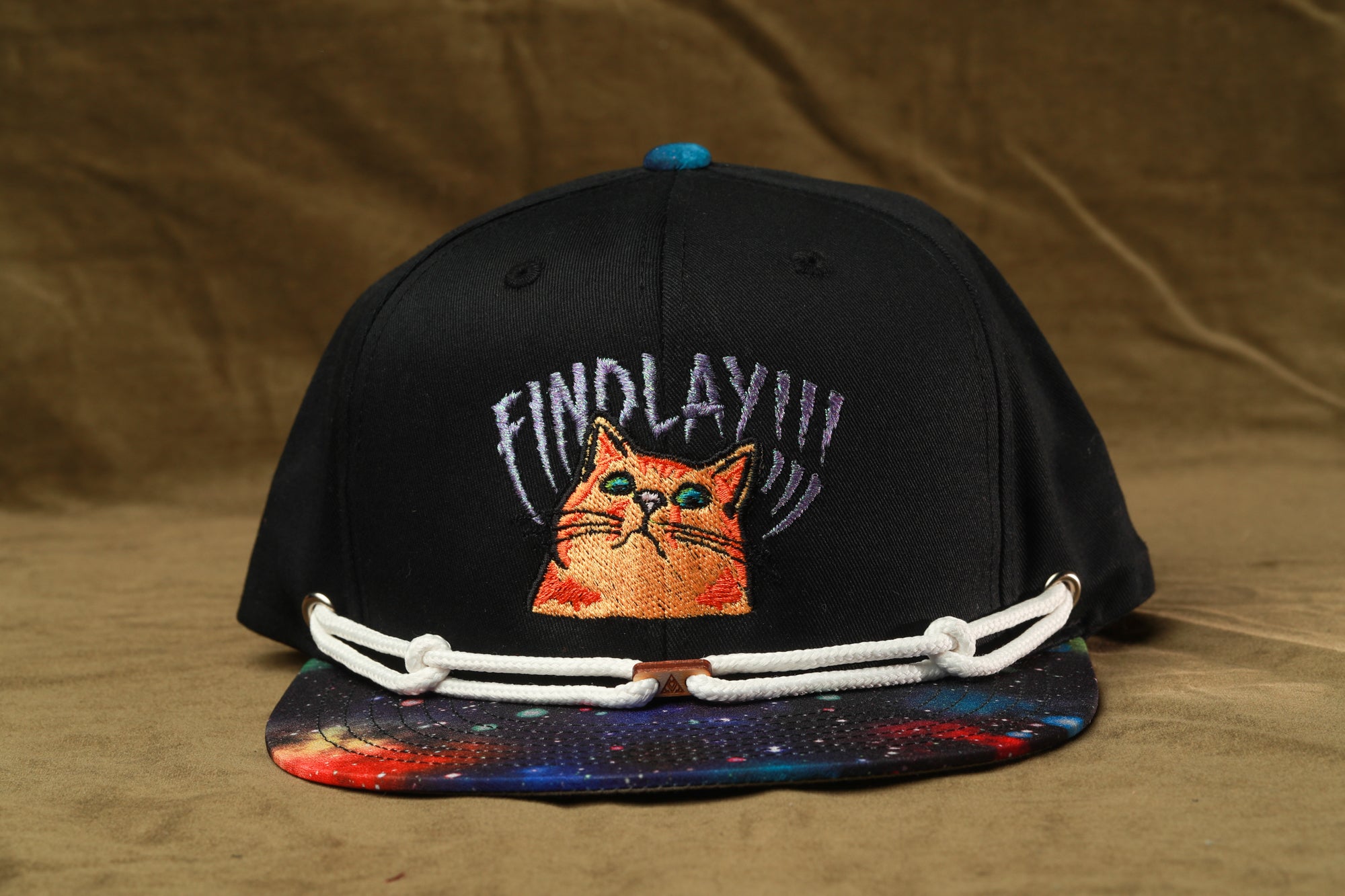A black baseball cap with a colorful galaxy print and a cat embroidered on it, featuring the text "FIND LAY!!!"