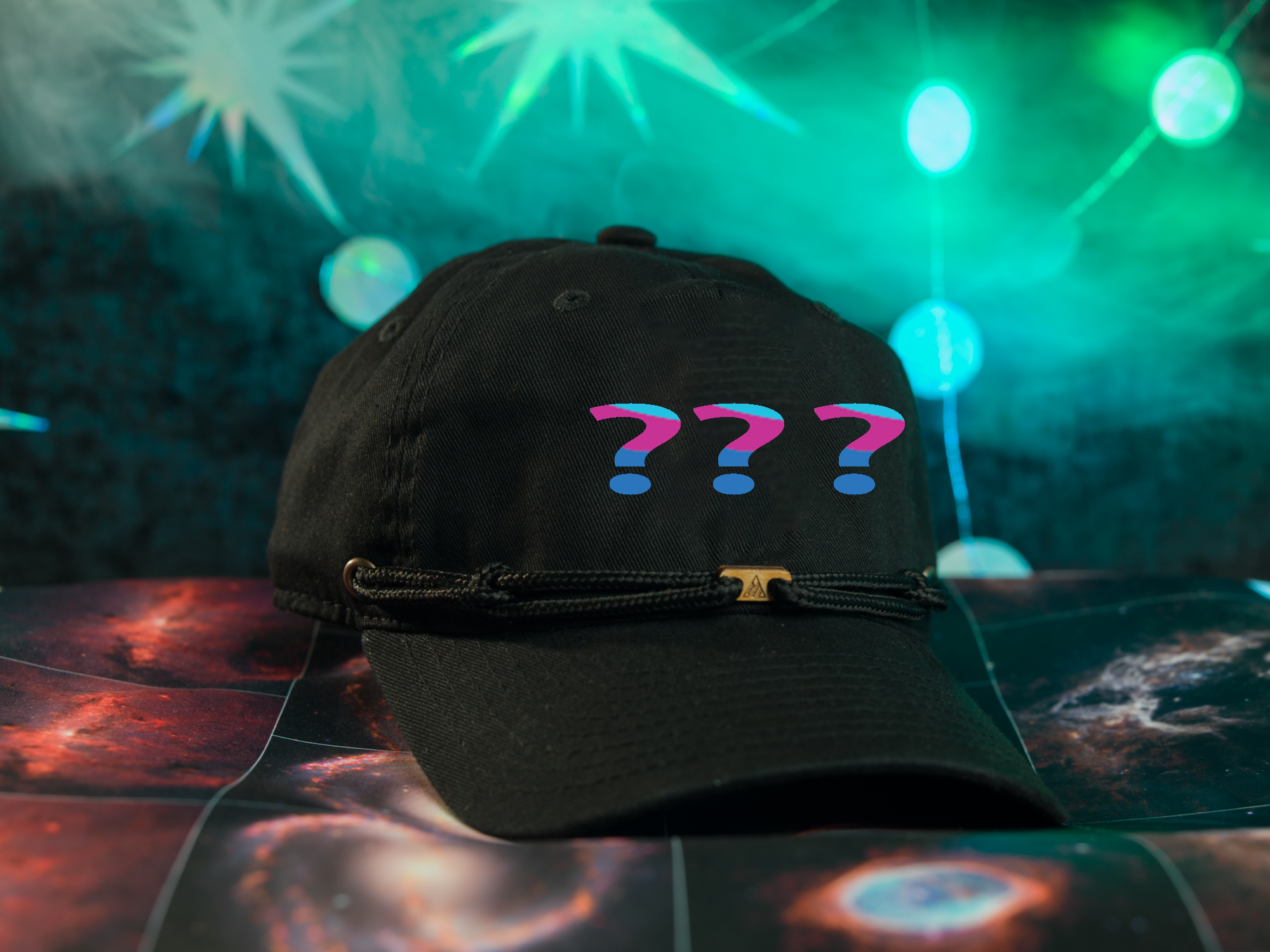 A black baseball cap with three question marks on it, placed on a surface with a colorful, starry background.