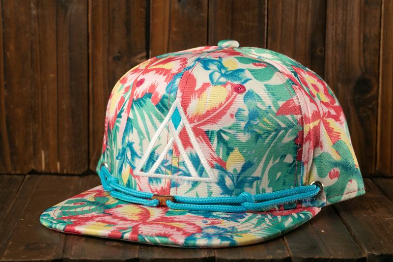 A colorful floral print baseball cap with a blue band, placed on a wooden surface against a wooden background.