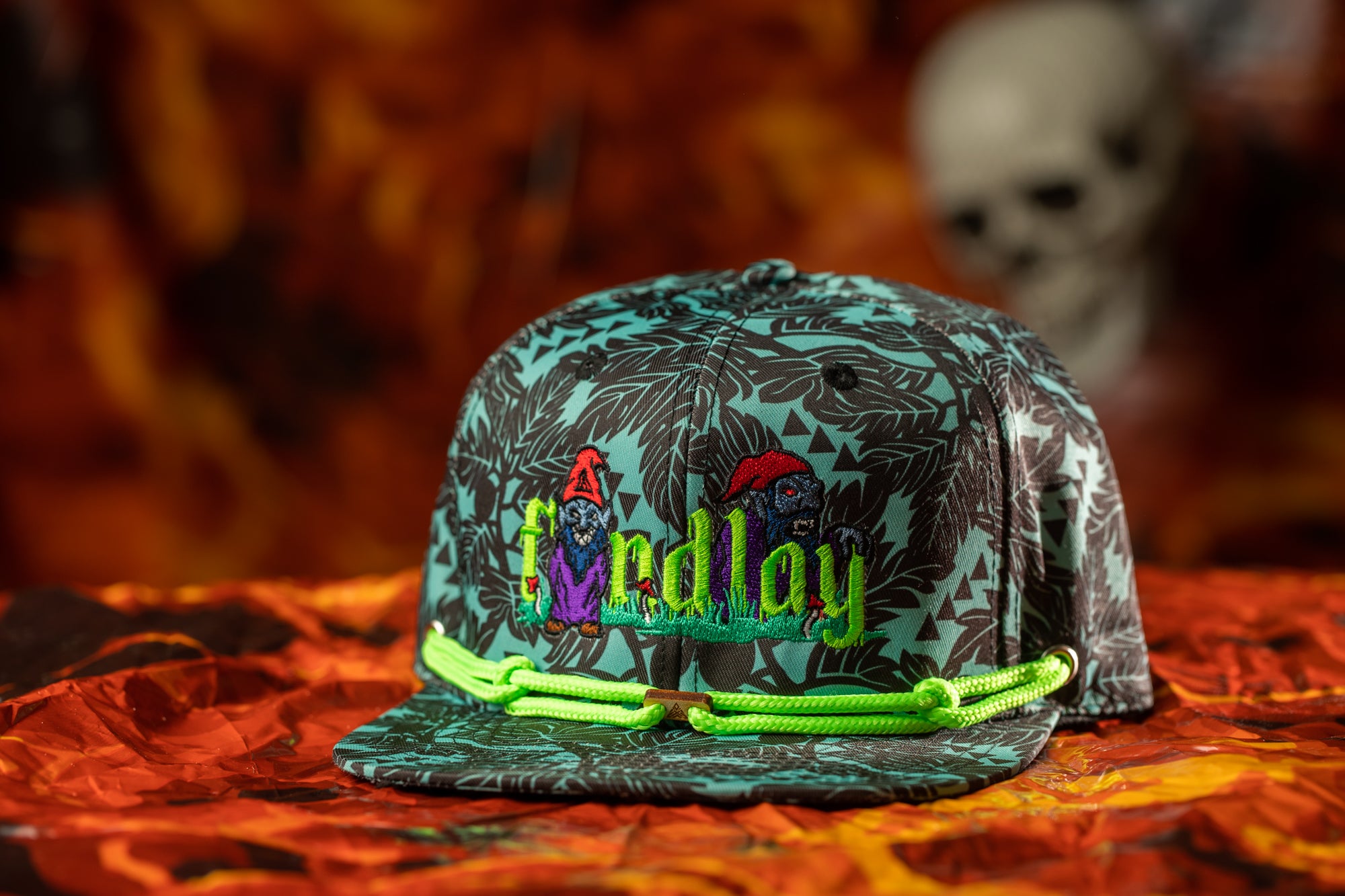 A colorful baseball cap with a floral pattern and the word "LAY" printed on it, placed on a red and orange background.