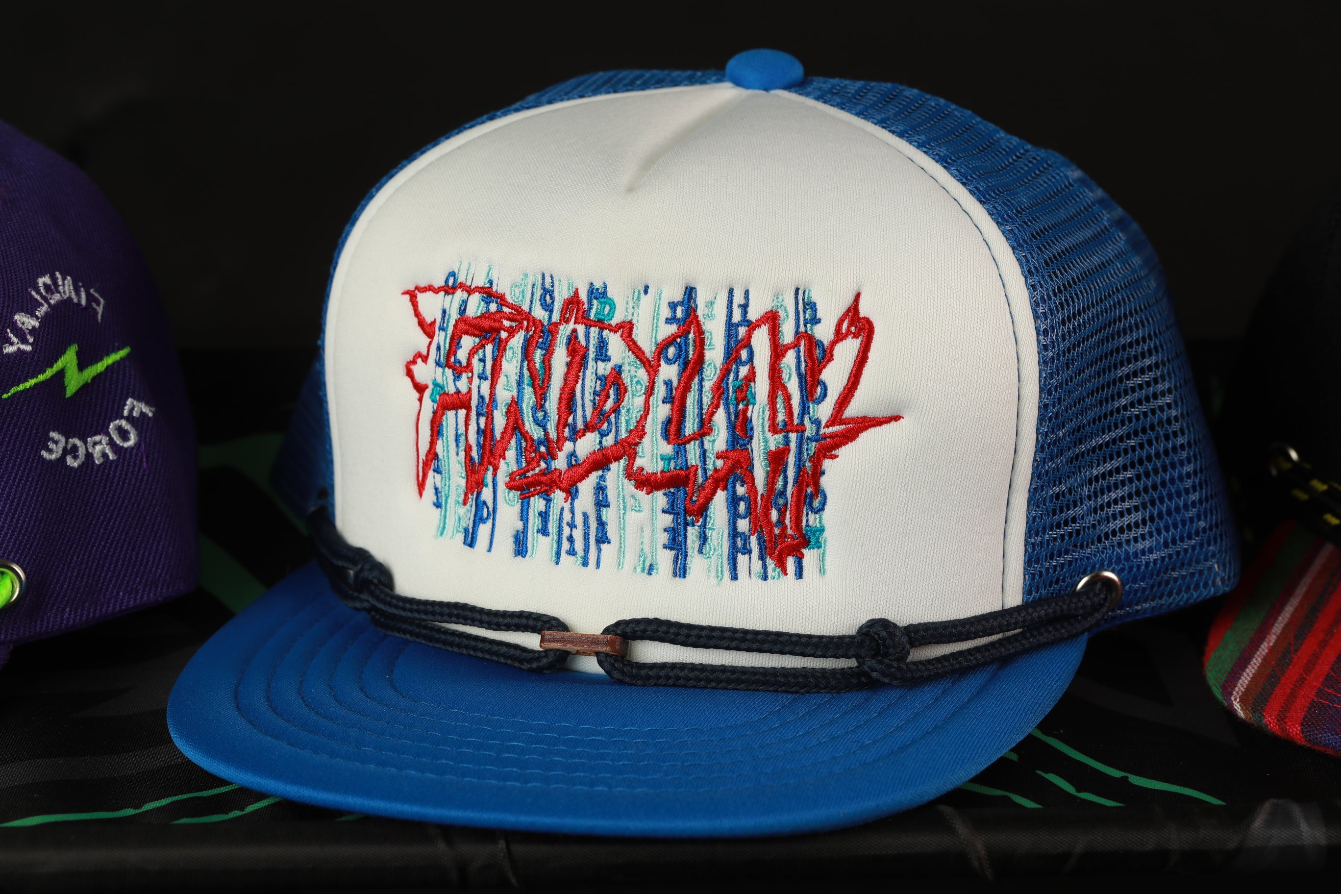 A blue and white baseball cap with a red and blue graffiti-style design on the front.