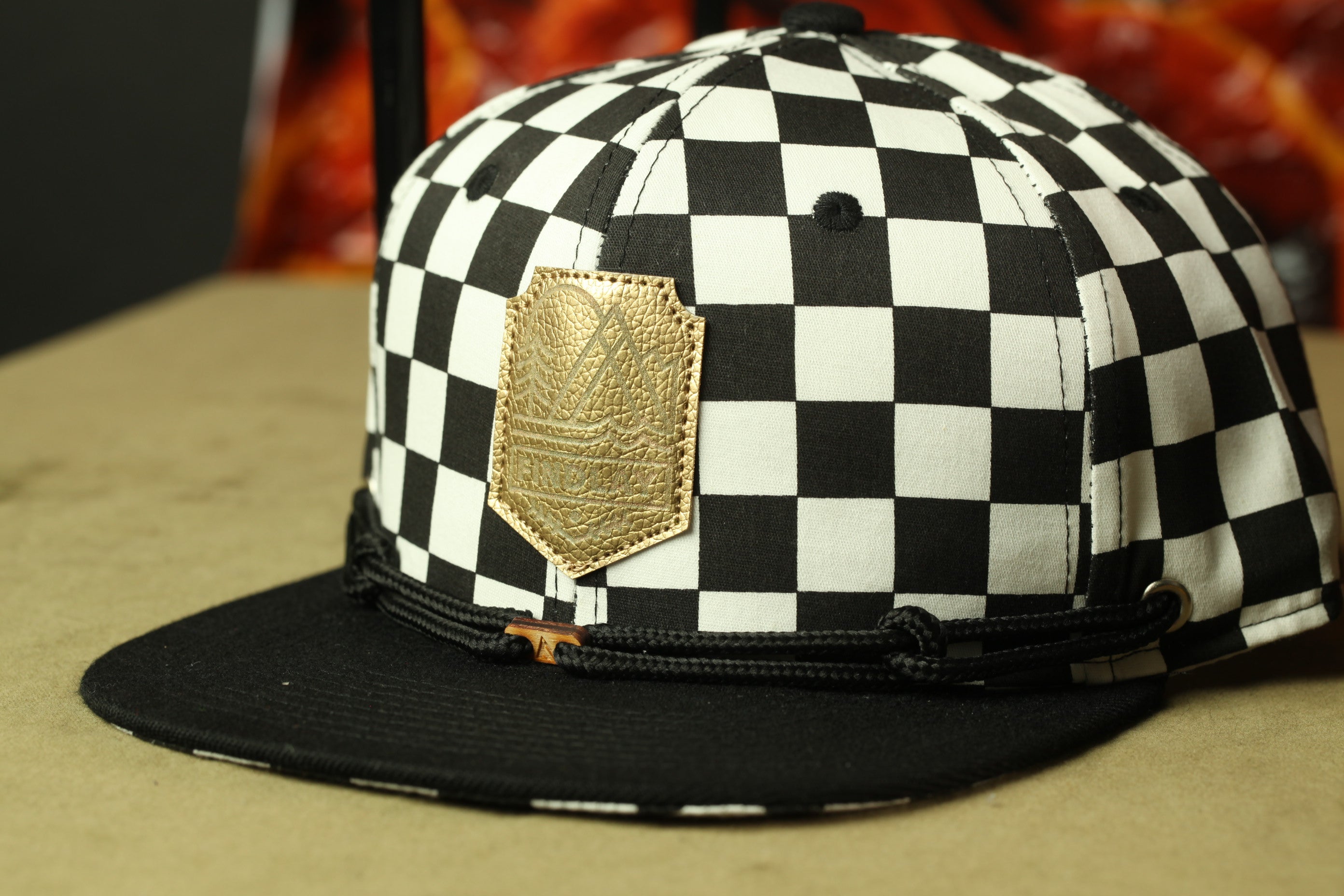 A black and white checkered baseball cap with a gold patch on the front.
