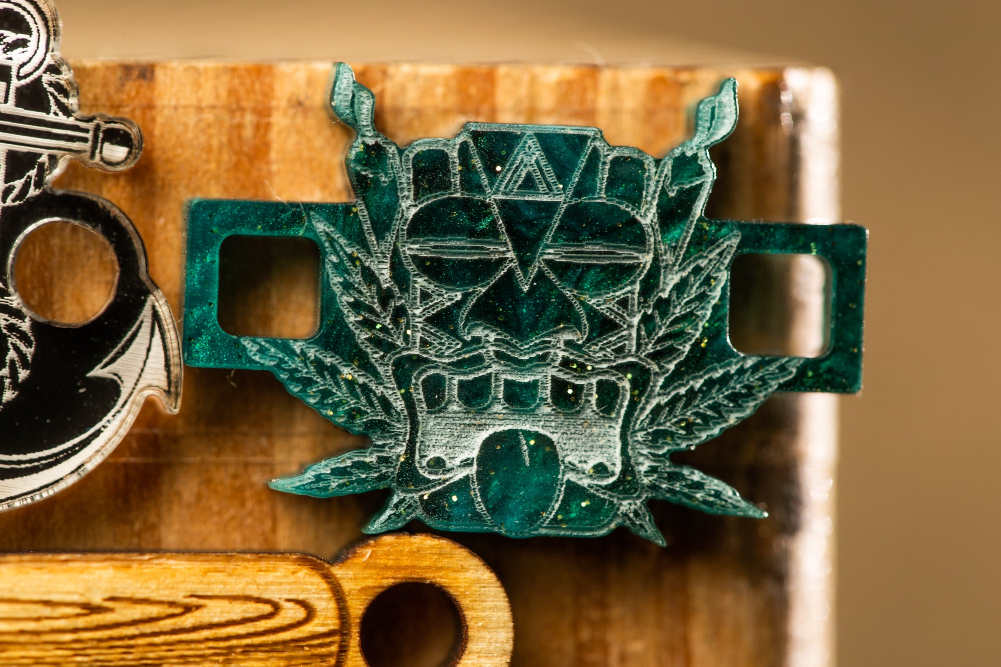 A close-up image of a green metal object with a skull-like design, featuring a leaf-like element and a triangular shape.