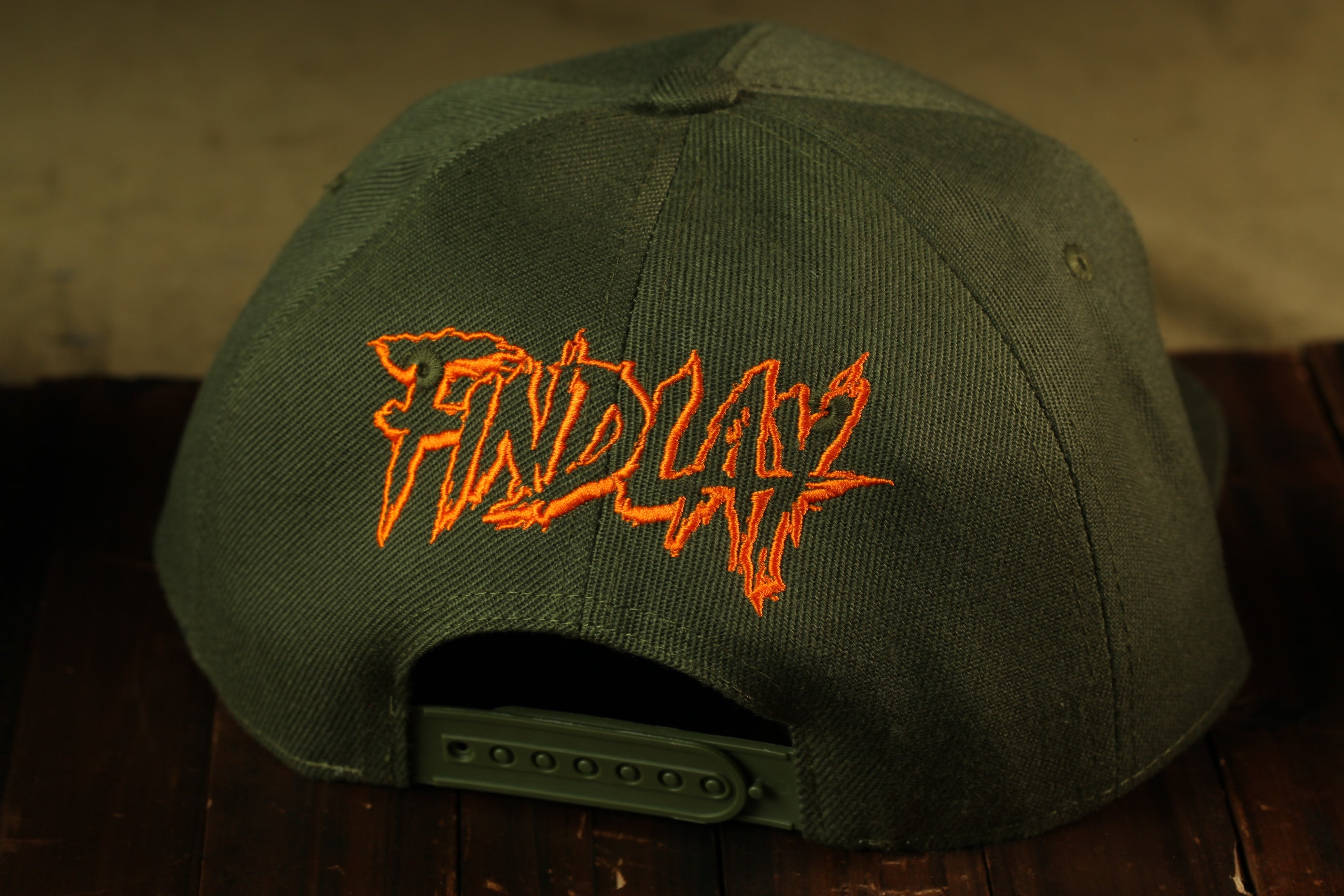 a green baseball cap with orange text on it.