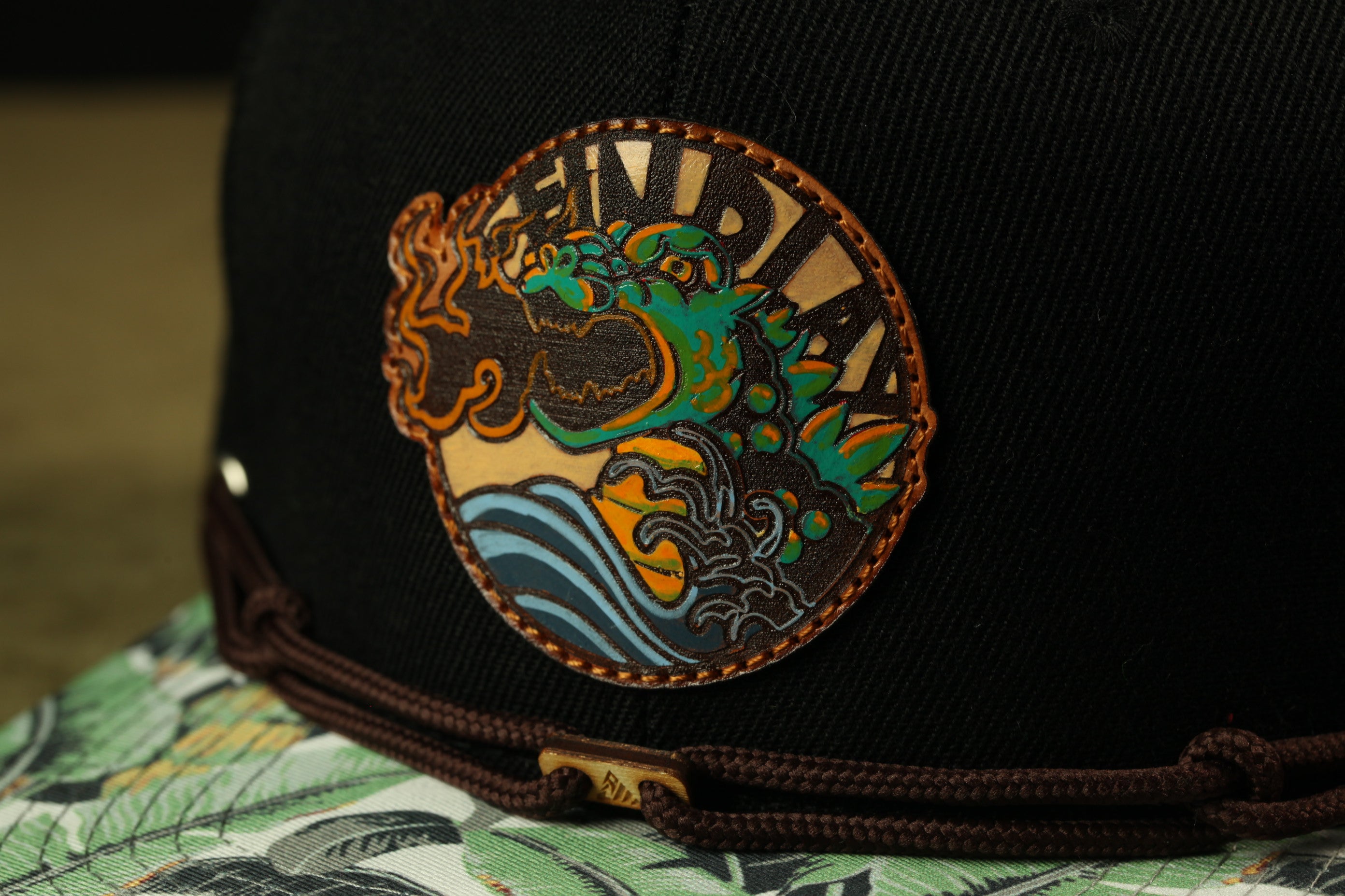 A close-up of a black baseball cap with a colorful, circular logo featuring a dragon-like creature.