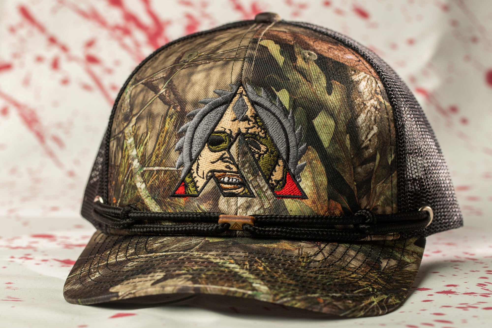 A camouflage baseball cap with a graphic design on the front.