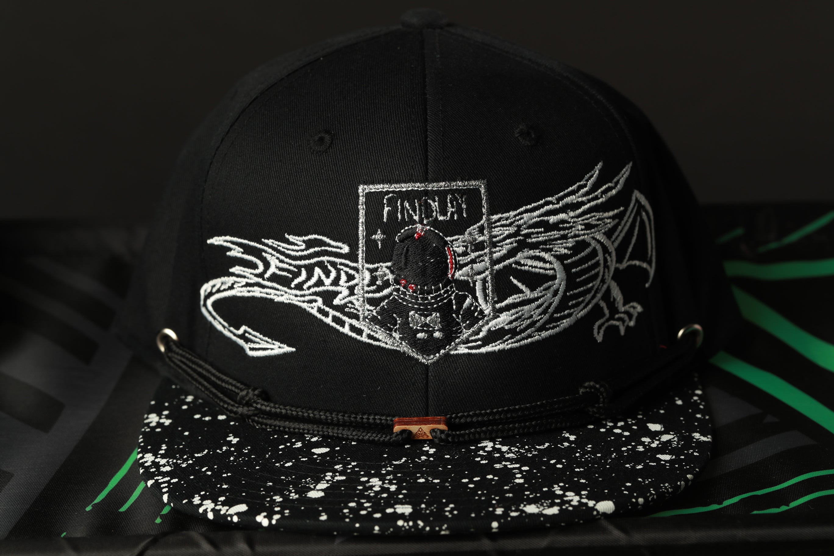 A black baseball cap with a white dragon design and the word "FINISH" printed on it.