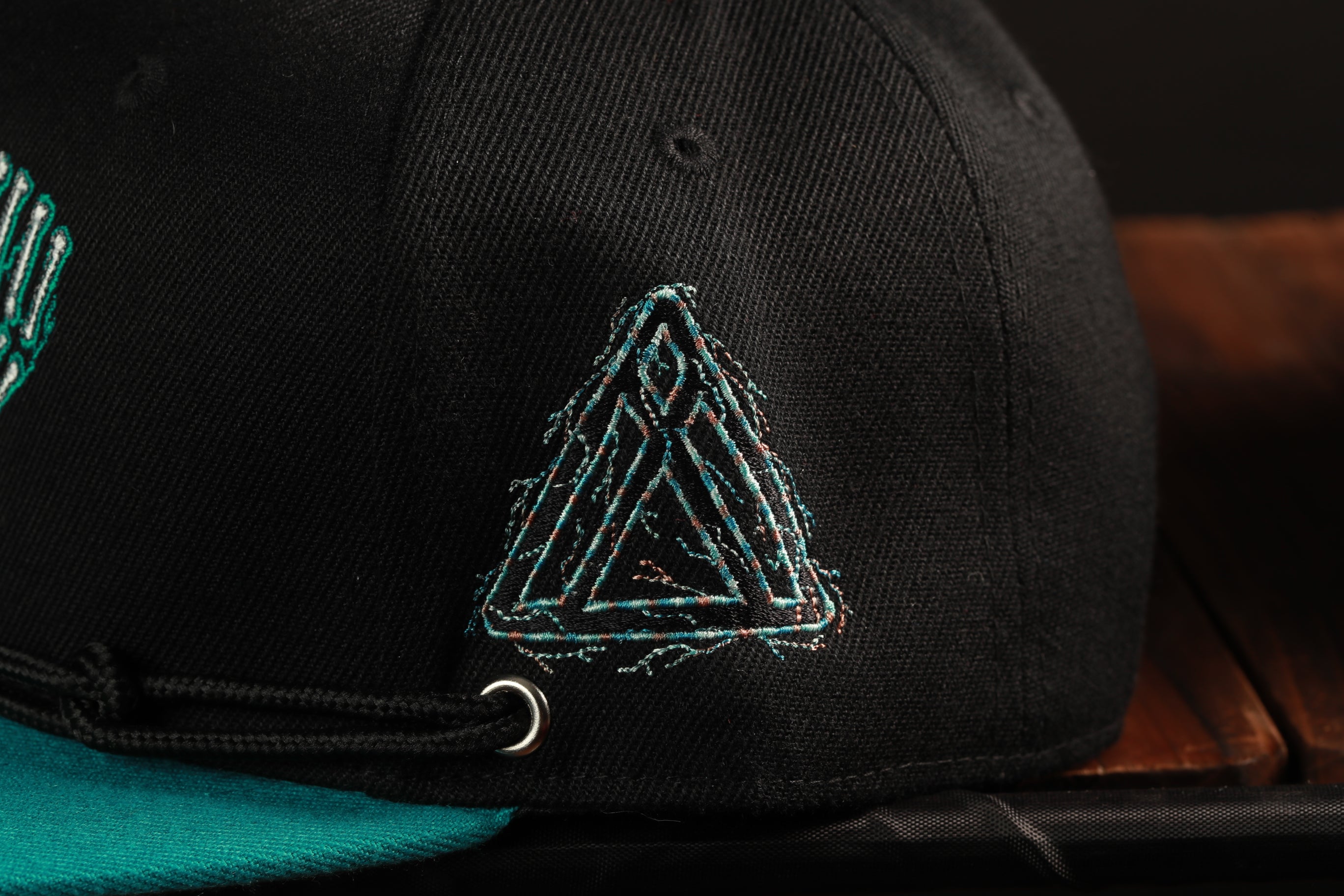 A close-up view of a black baseball cap with a geometric pattern on the front.