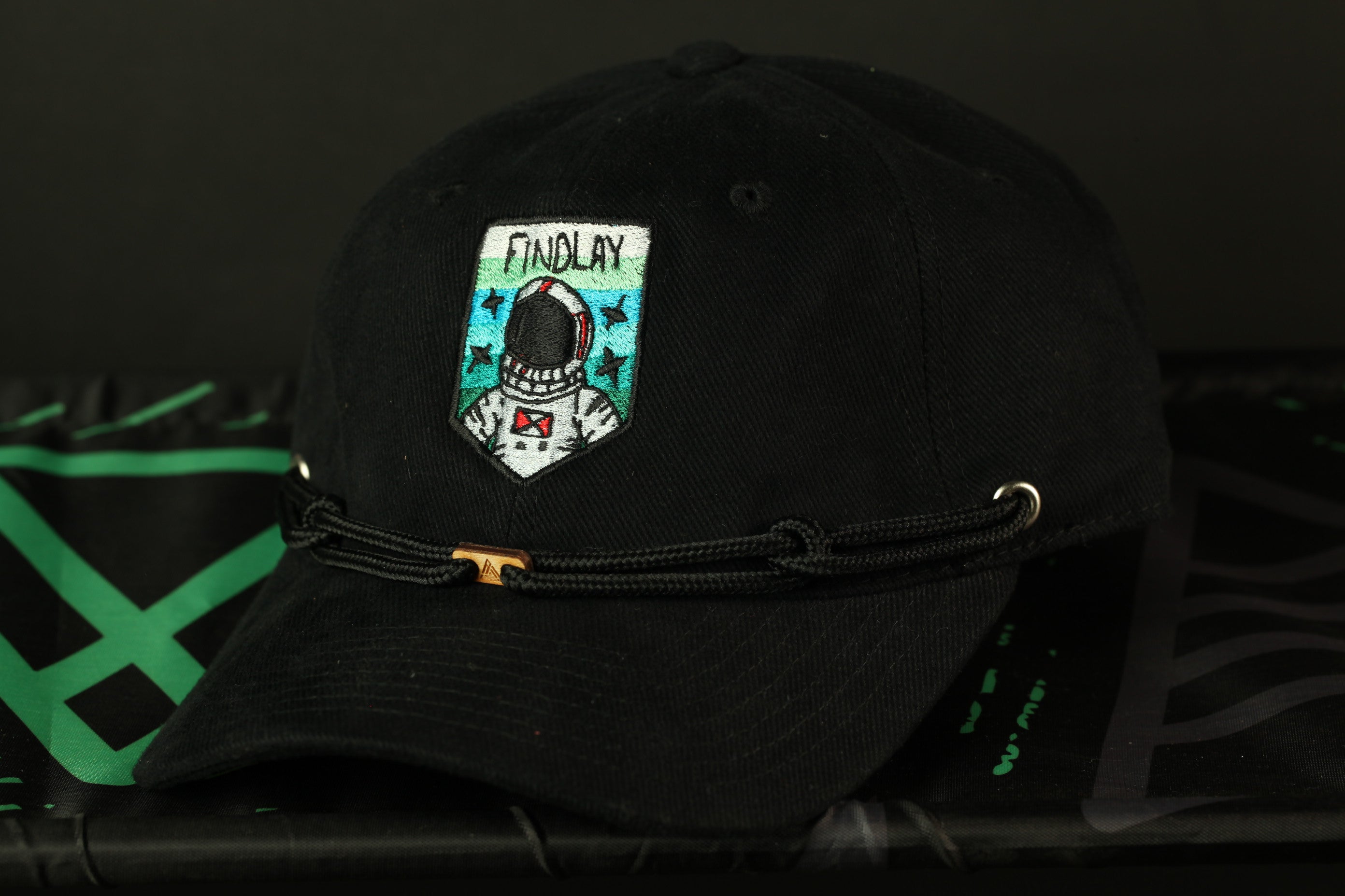 A black baseball cap with a patch featuring an astronaut and the word "FINDLAY" on it.