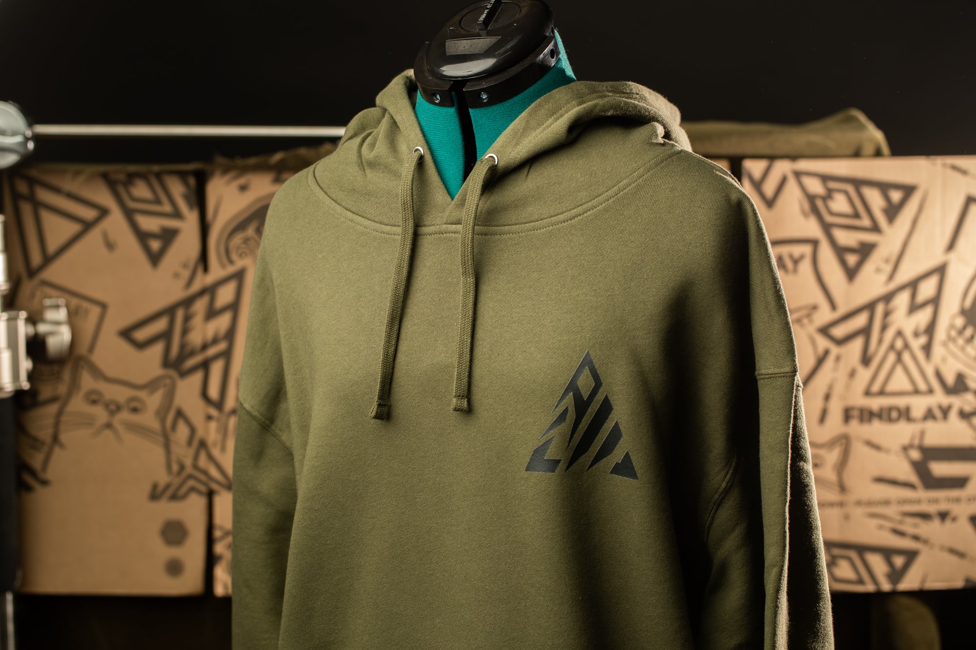 A mannequin wearing a green hoodie with a black triangle design on the front.