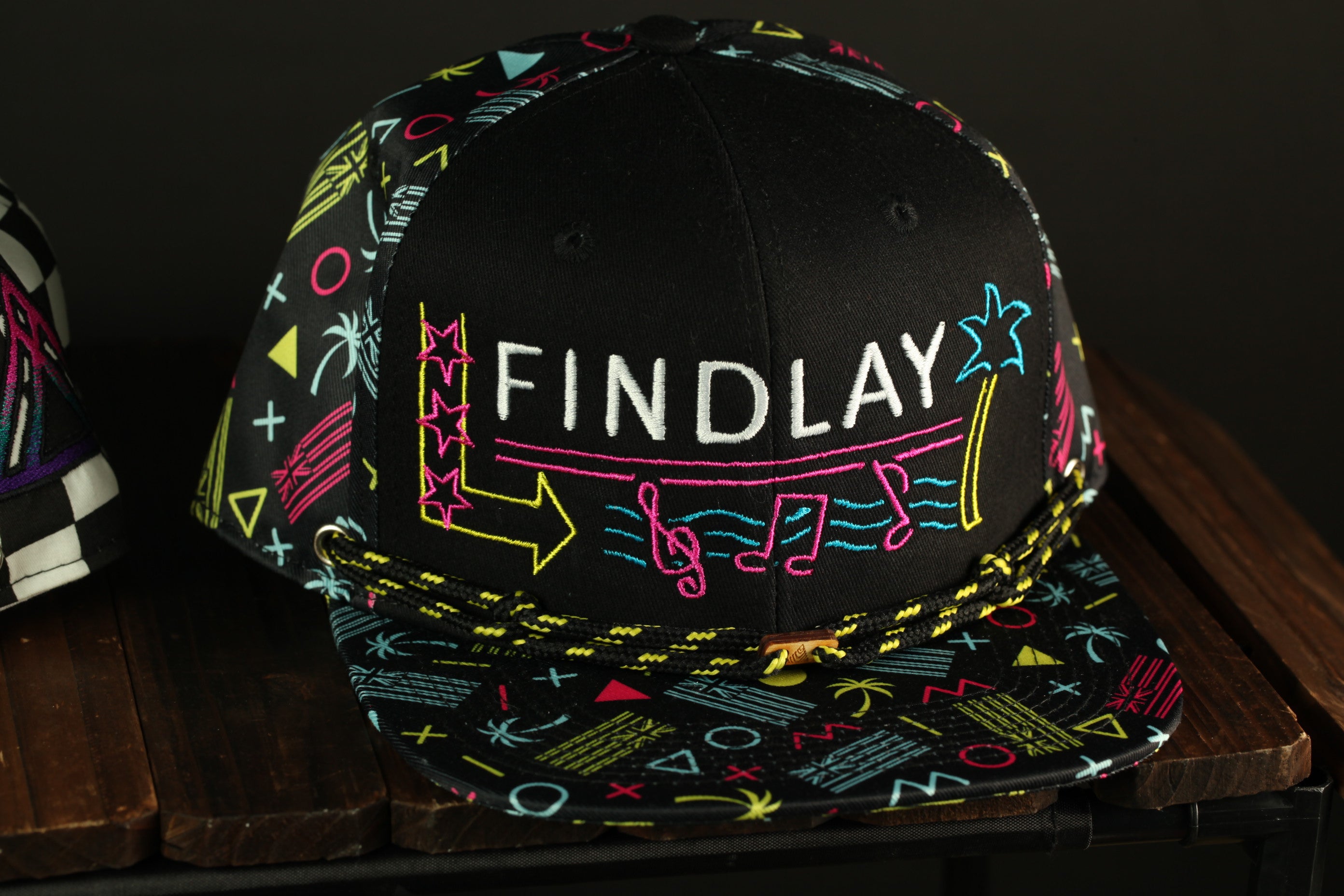 A colorful baseball cap with the word "FINDlay" printed on it, sitting on a wooden surface.