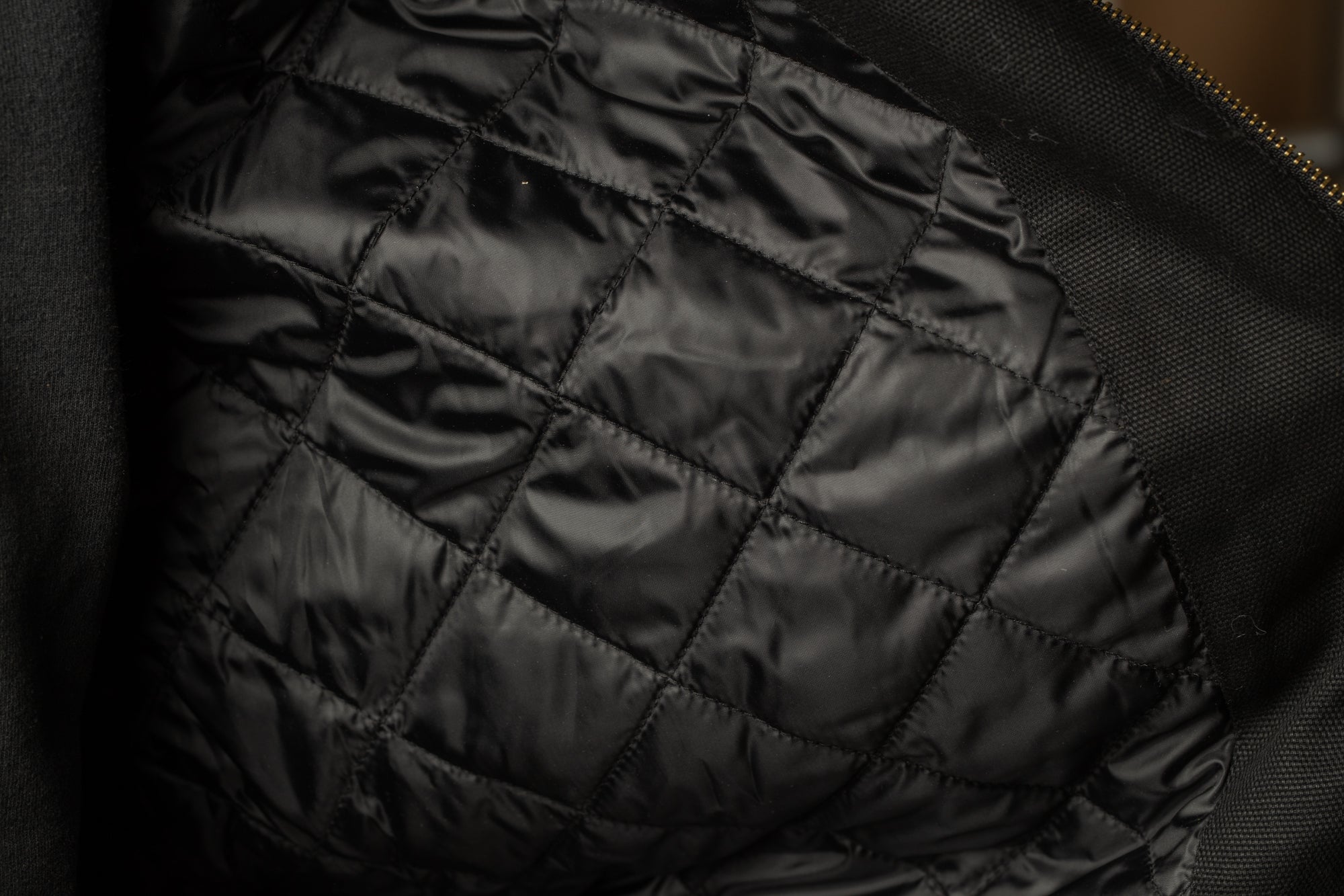 a close-up view of a black fabric with a quilted pattern, likely a jacket or blanket.
