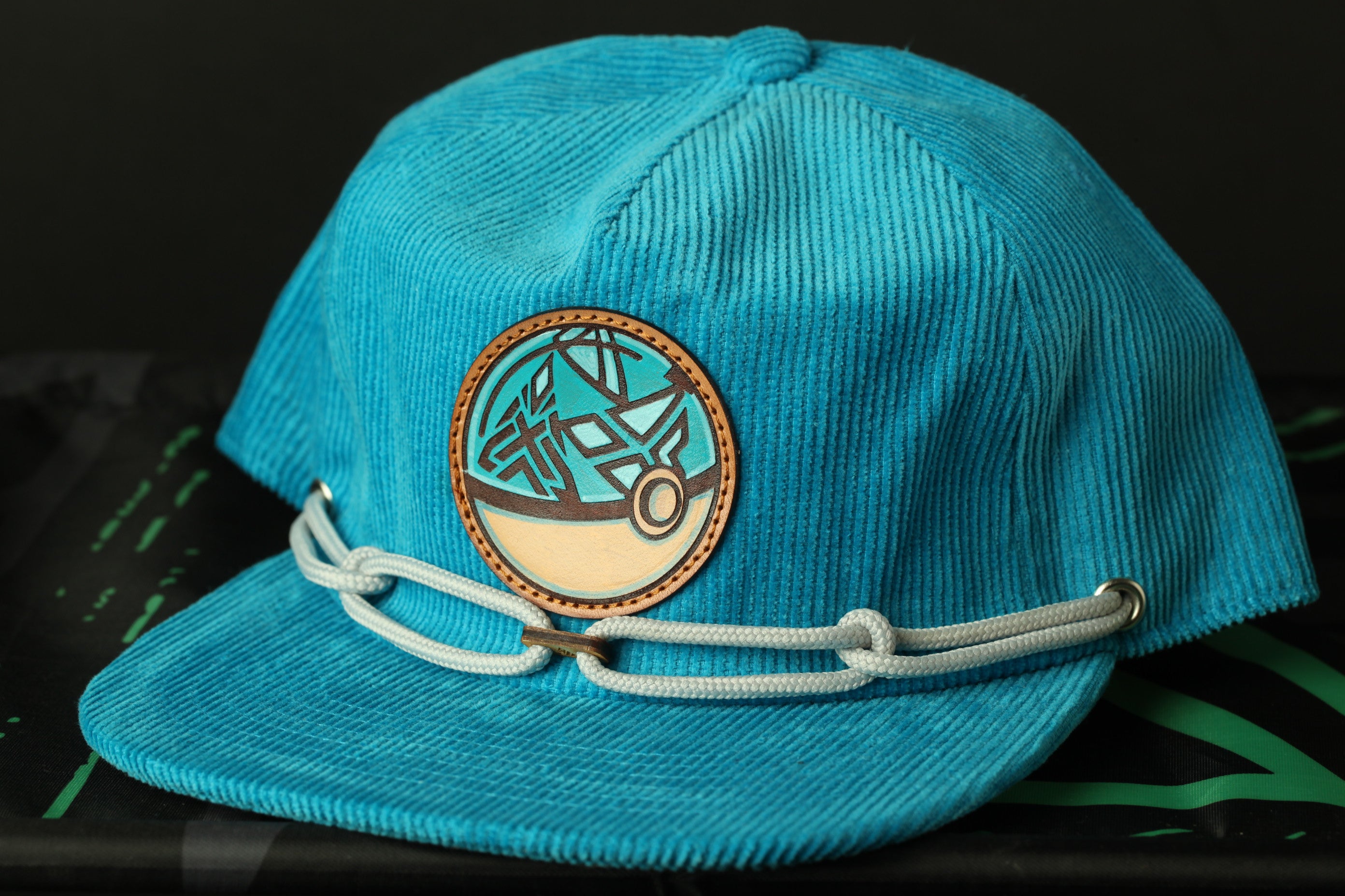 A blue baseball cap with a circular patch on the front, featuring a graphic design.