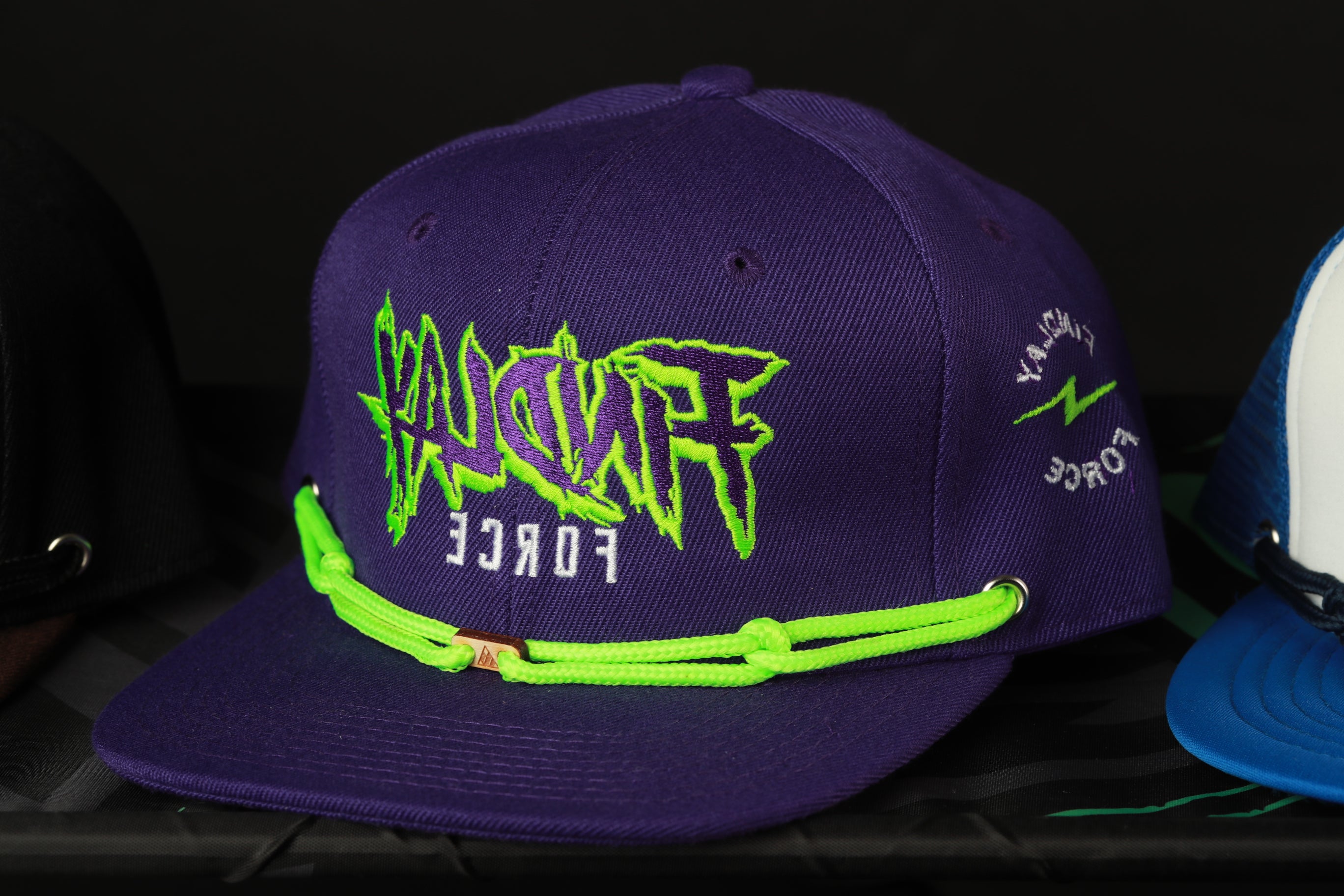 A purple baseball cap with neon green text and a rope strap.