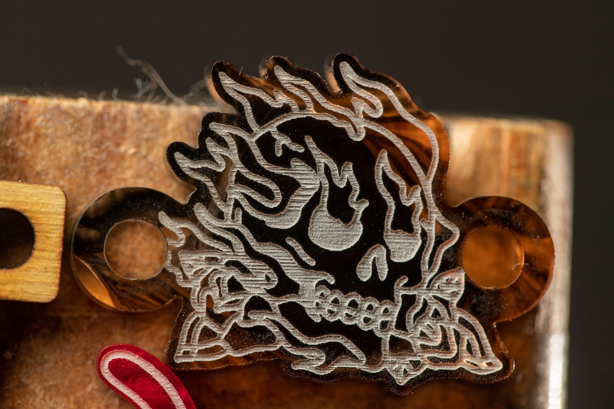 a close-up view of a black and white engraved skull design on a wooden surface.