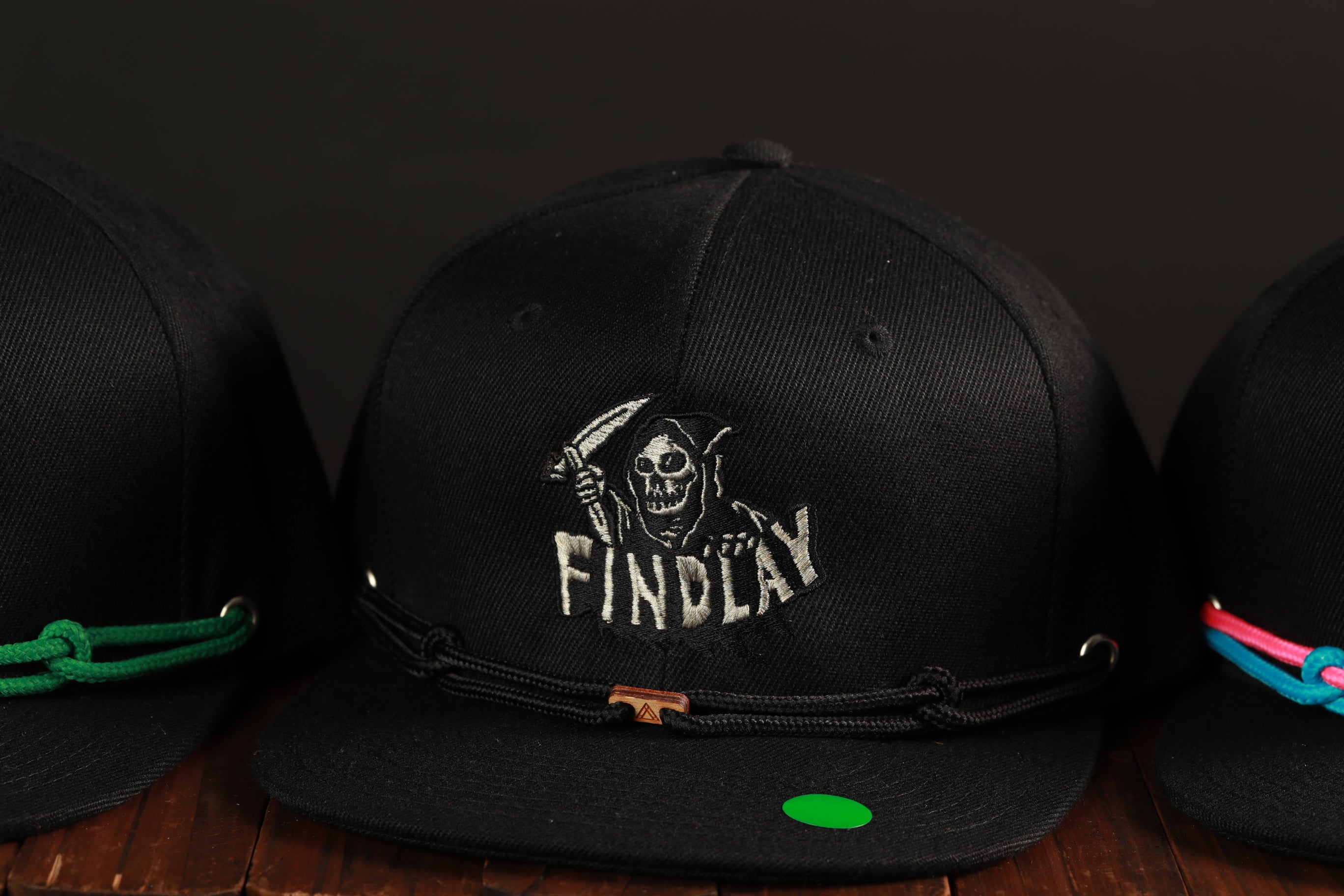 A close-up view of a black baseball cap with a skull and crossbones design, featuring the word "FINDA" on the front.