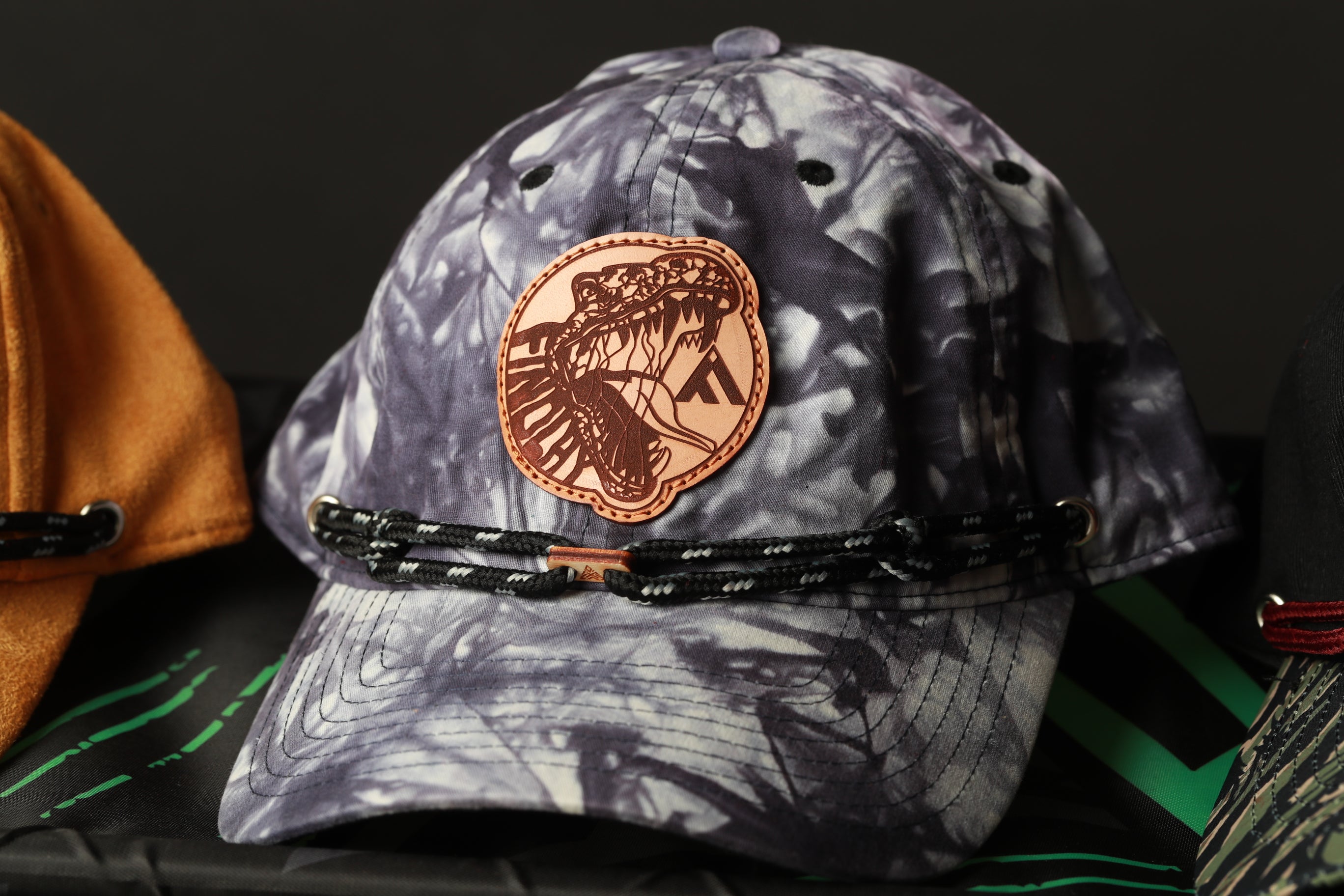 A close-up image of a tie-dye baseball cap with a distinctive logo on the front.