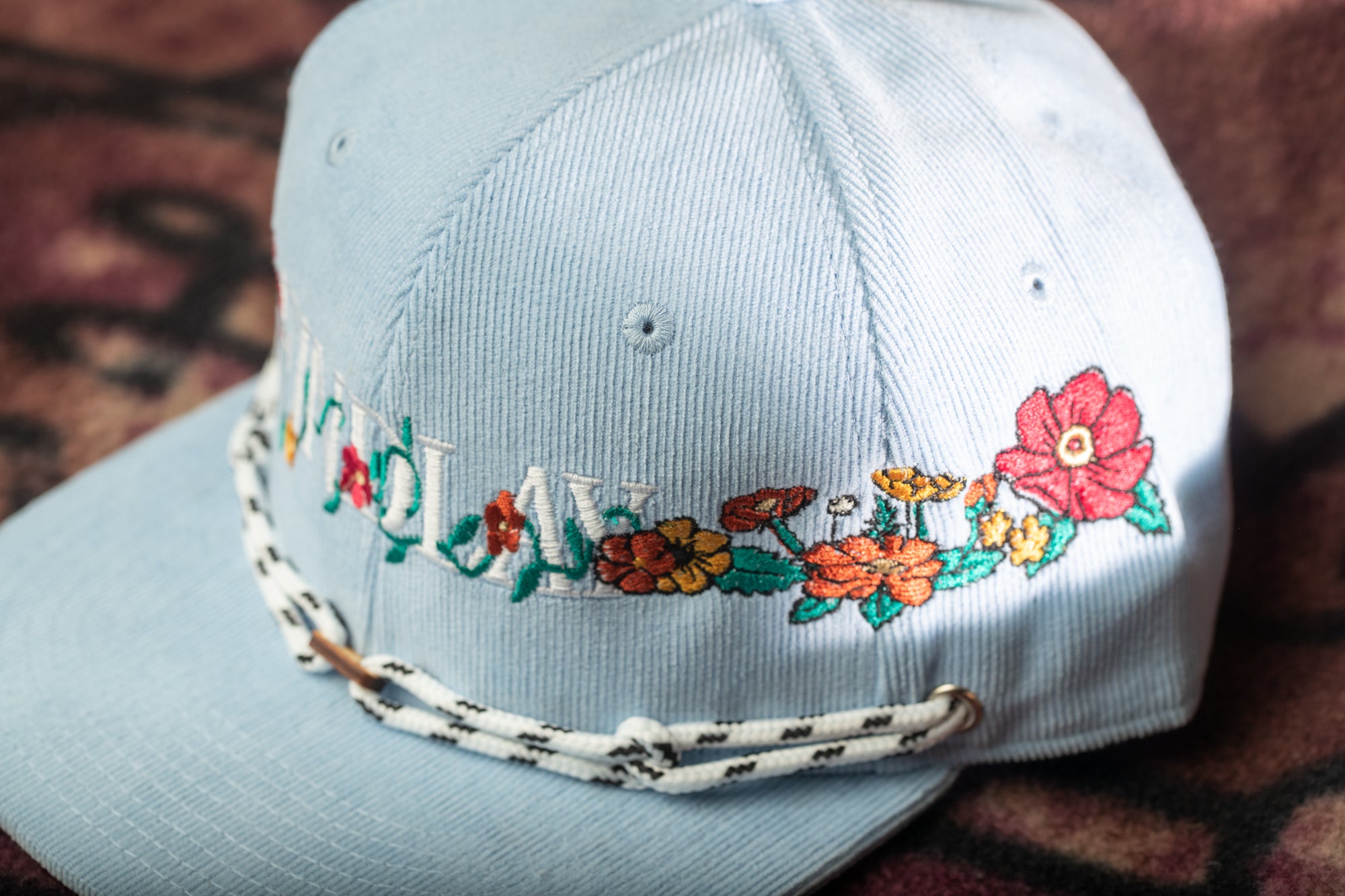 A light blue baseball cap with a floral embroidered design on the front.