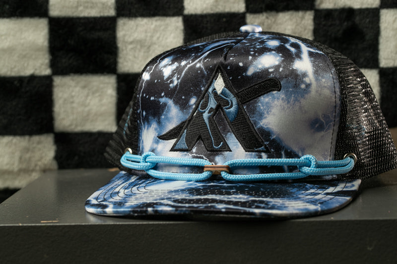 A black and white checkered background with a black and white patterned baseball cap featuring a graphic design on the front.