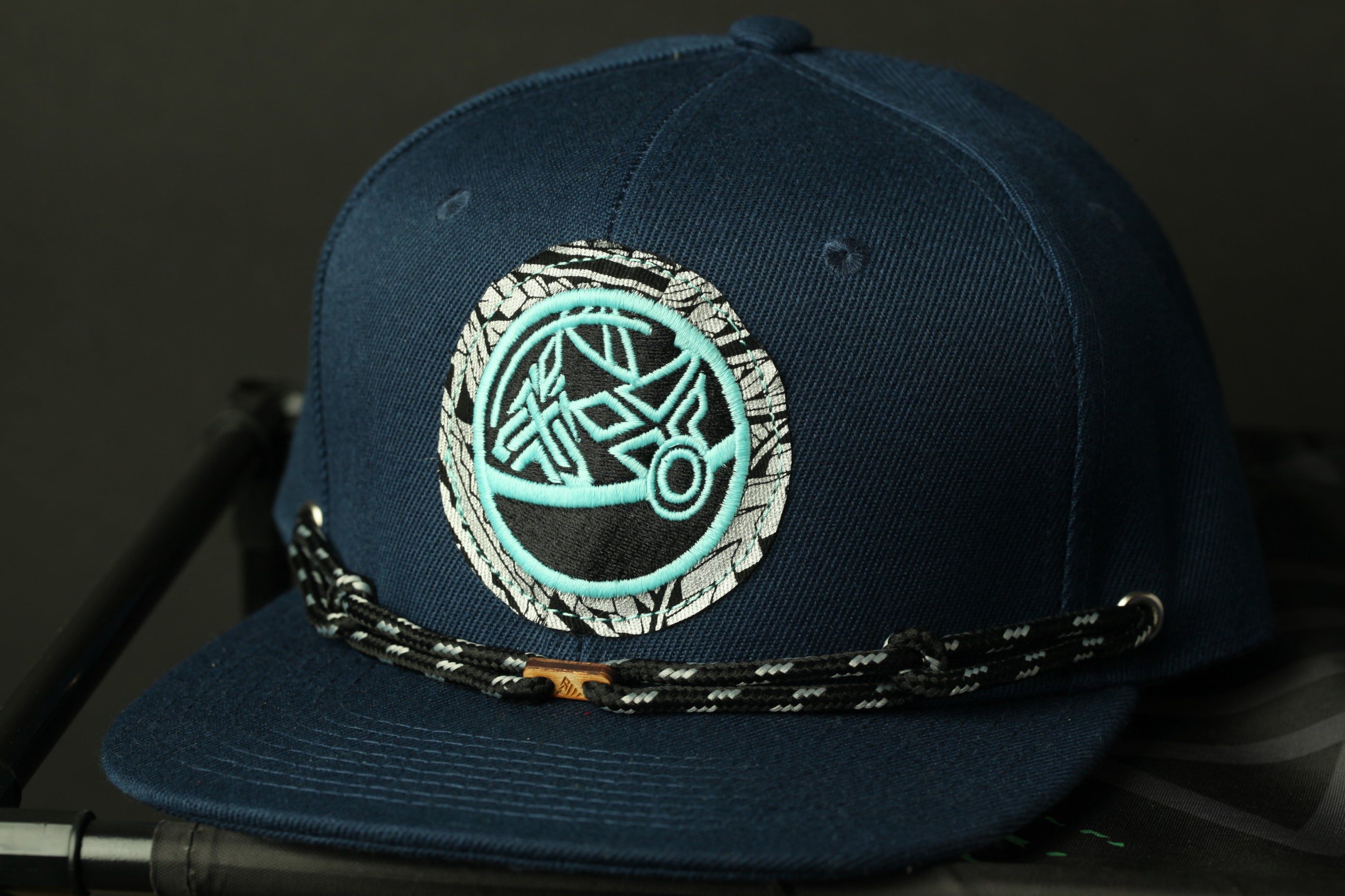 A navy blue baseball cap with a circular embroidered logo on the front.