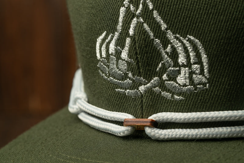 A close-up view of a green baseball cap with a white embroidered logo on the front.