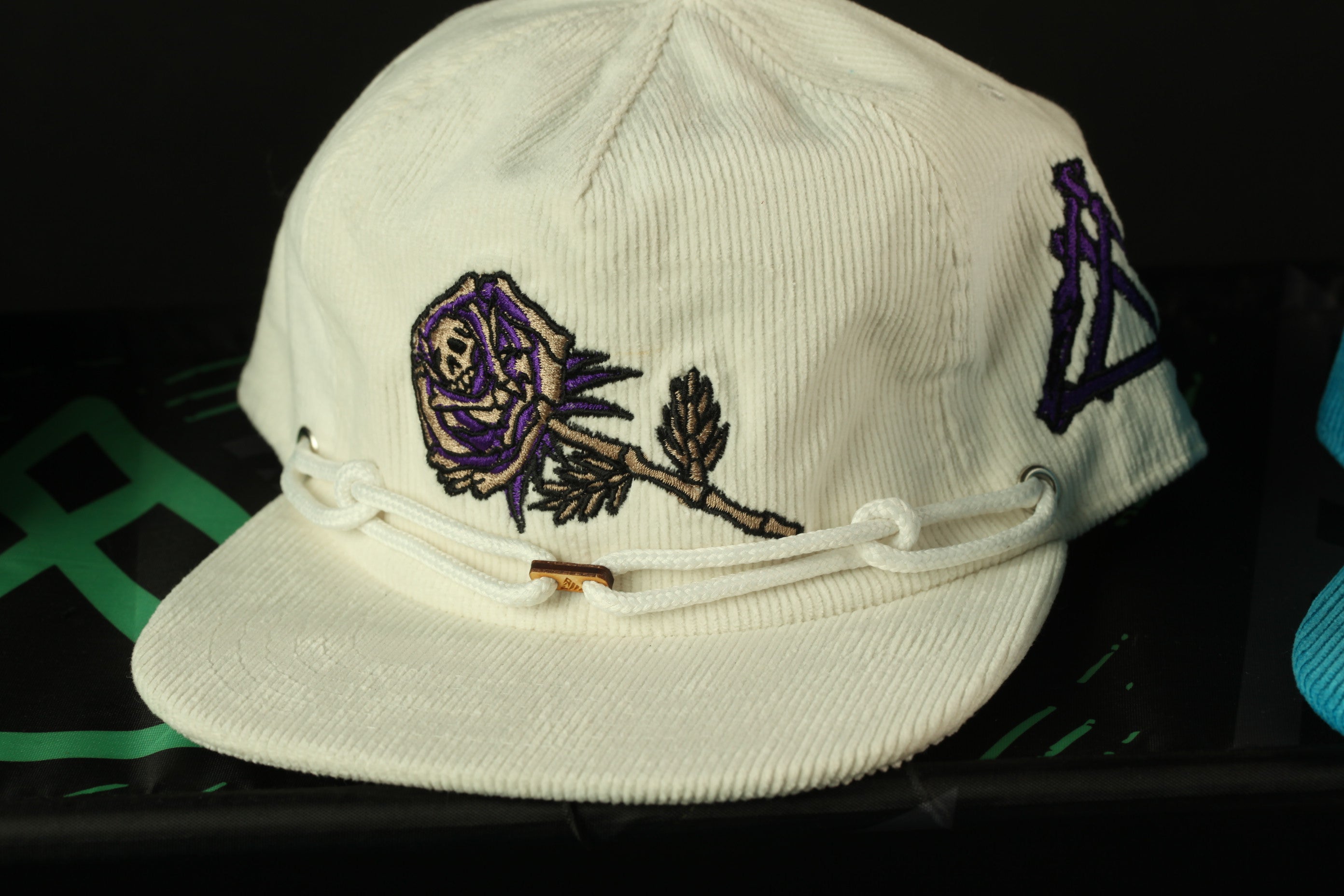 A white baseball cap with a purple and black embroidered design on the front.
