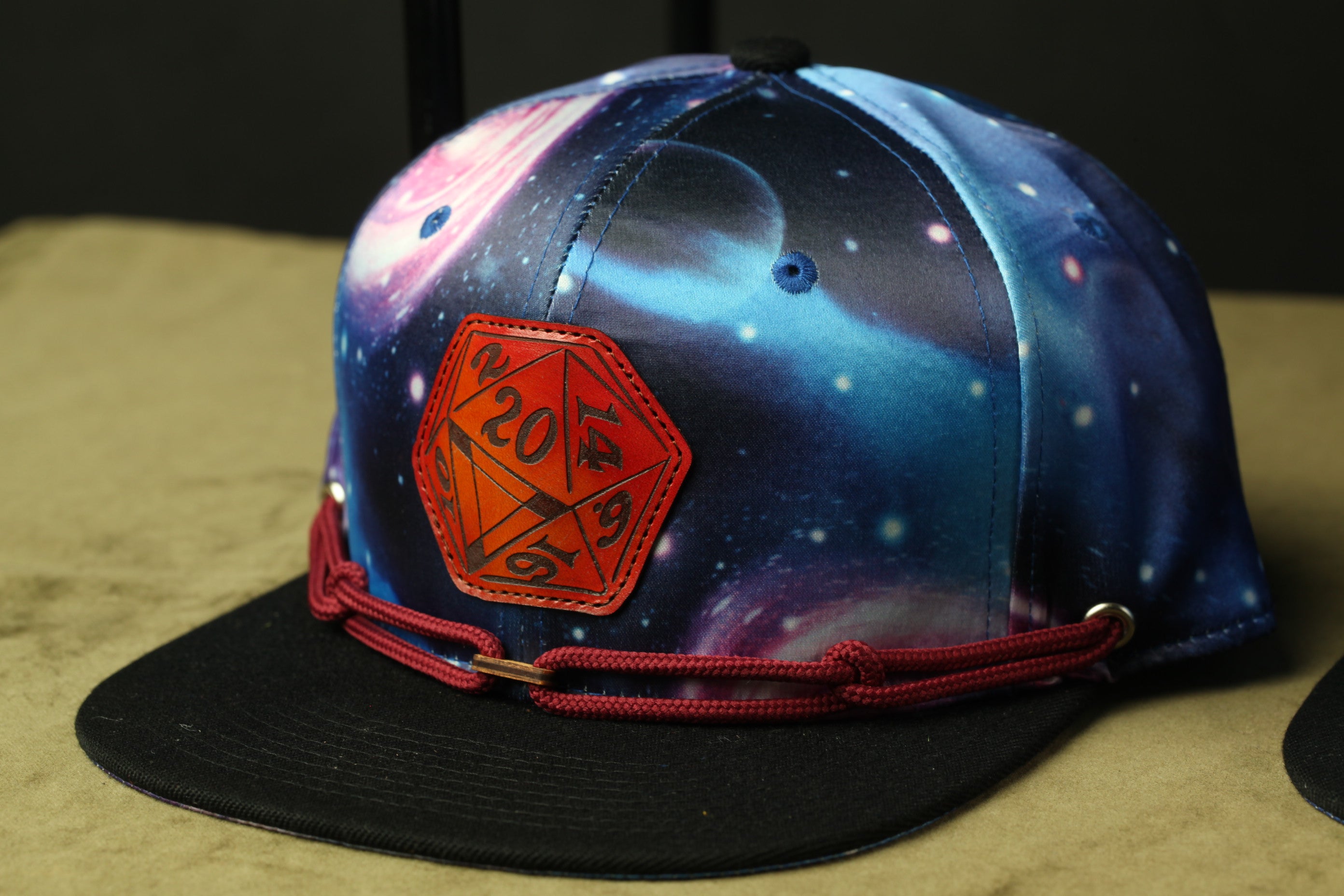 A colorful baseball cap with a space-themed design, featuring a red hexagon with the number "20" on it.