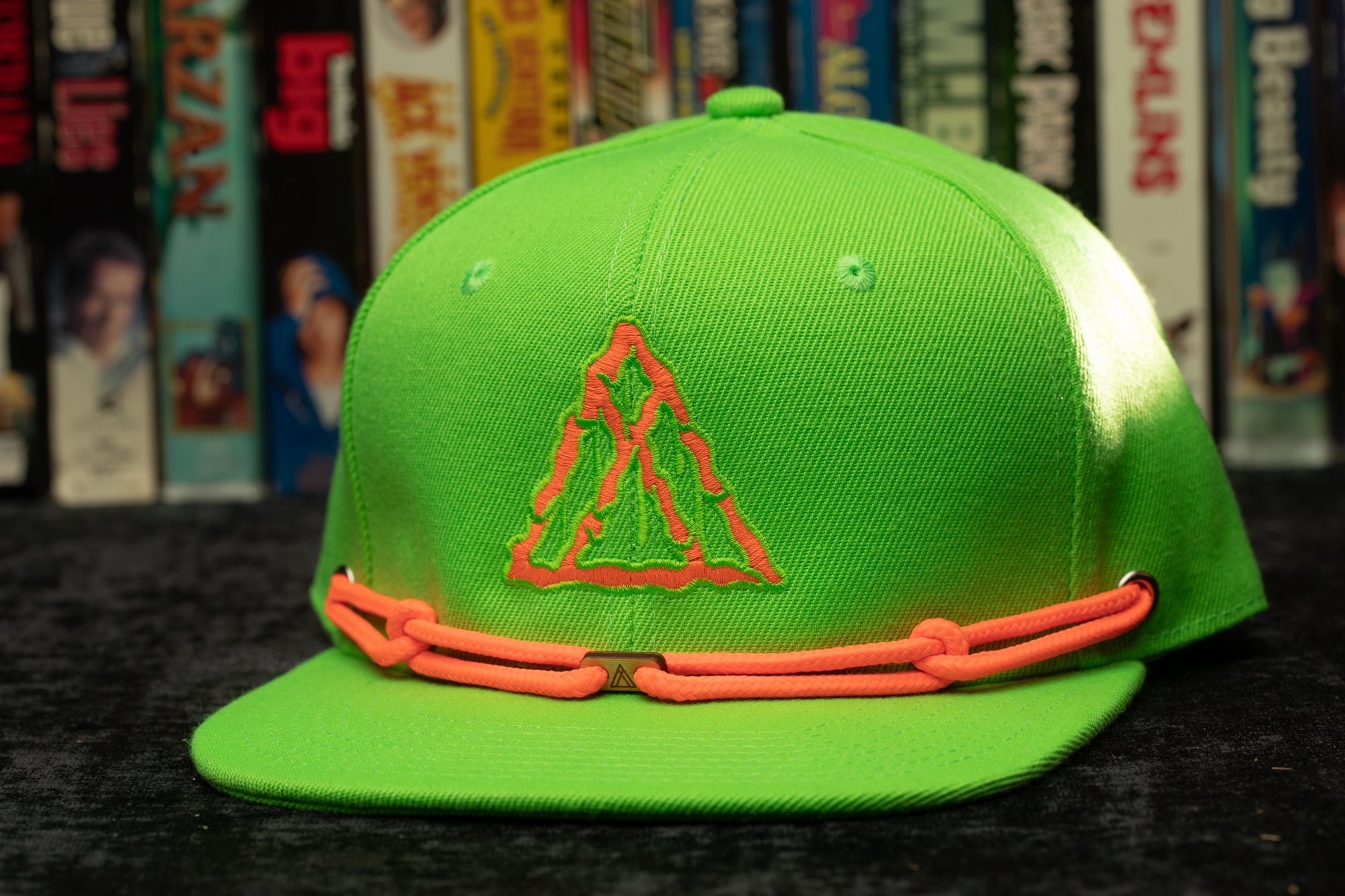a green hat with an orange band around the peak