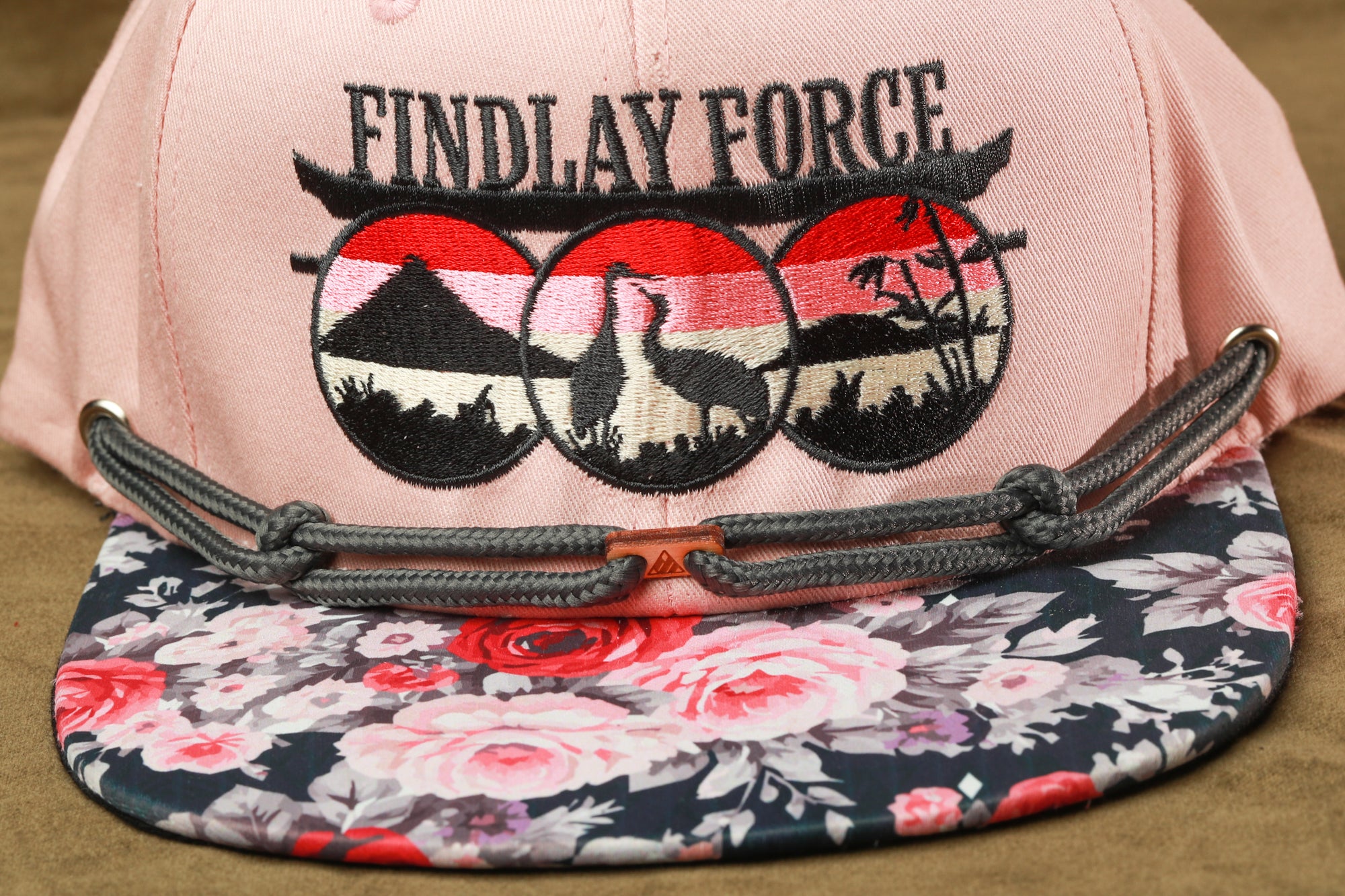 A pink baseball cap with a floral pattern and the text "FINDLAY FORCE" printed on it.