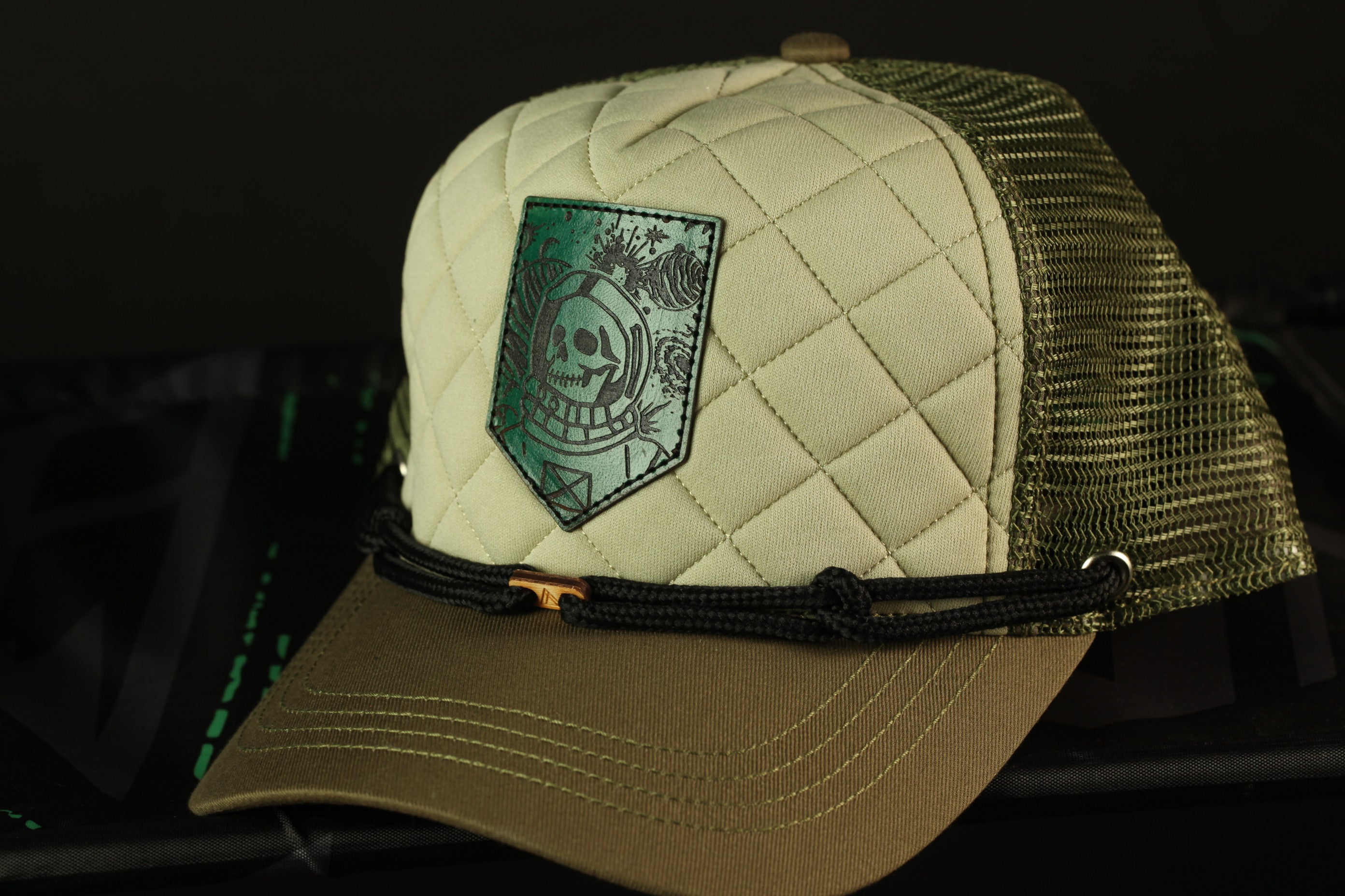 A beige baseball cap with a mesh back and a patch featuring a skull and crossbones design on the front.